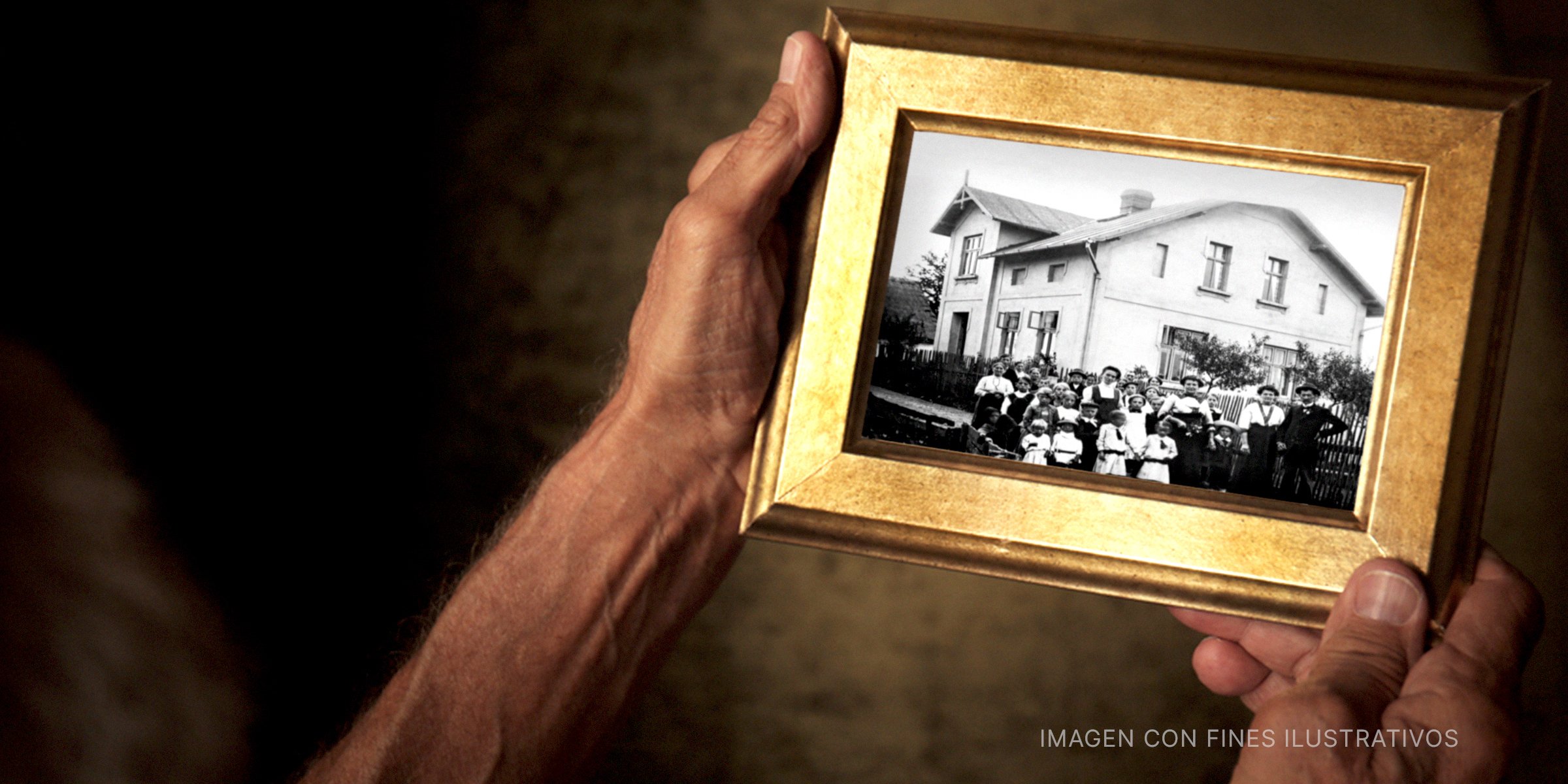 Manos sosteniendo una fotografía enmarcada de una casa | Foto: Shutterstock