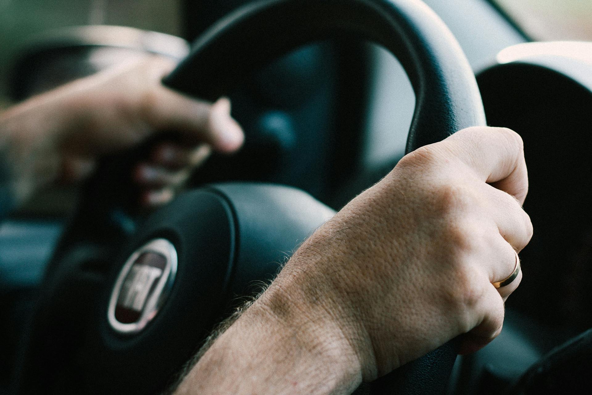 Close-up of a man's hands on a steering wheel | Source: Pexels