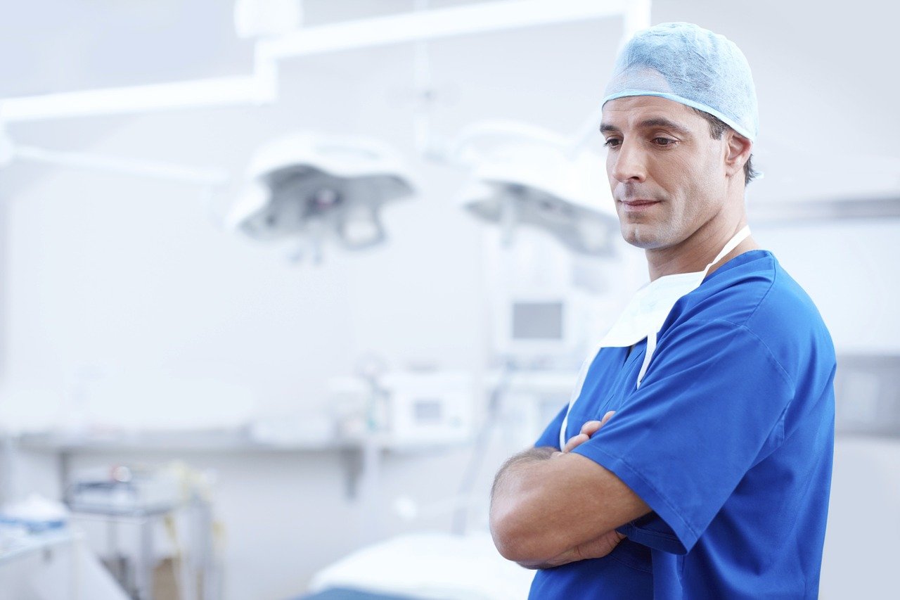 A doctor wearing blue scrubs with his hands folded at a hospital | Photo: Pixabay