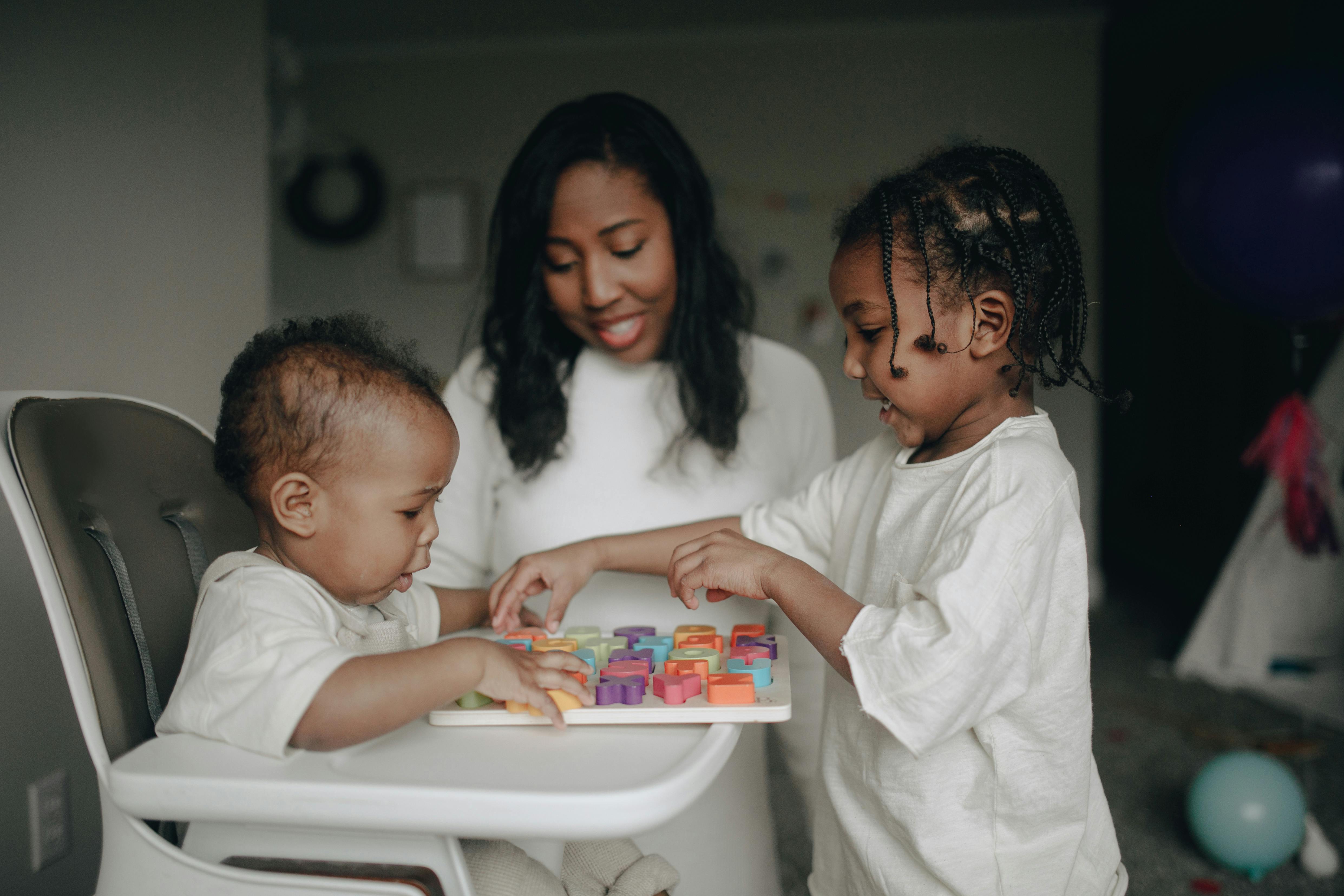 A woman interacting with two children | Source: Pexels