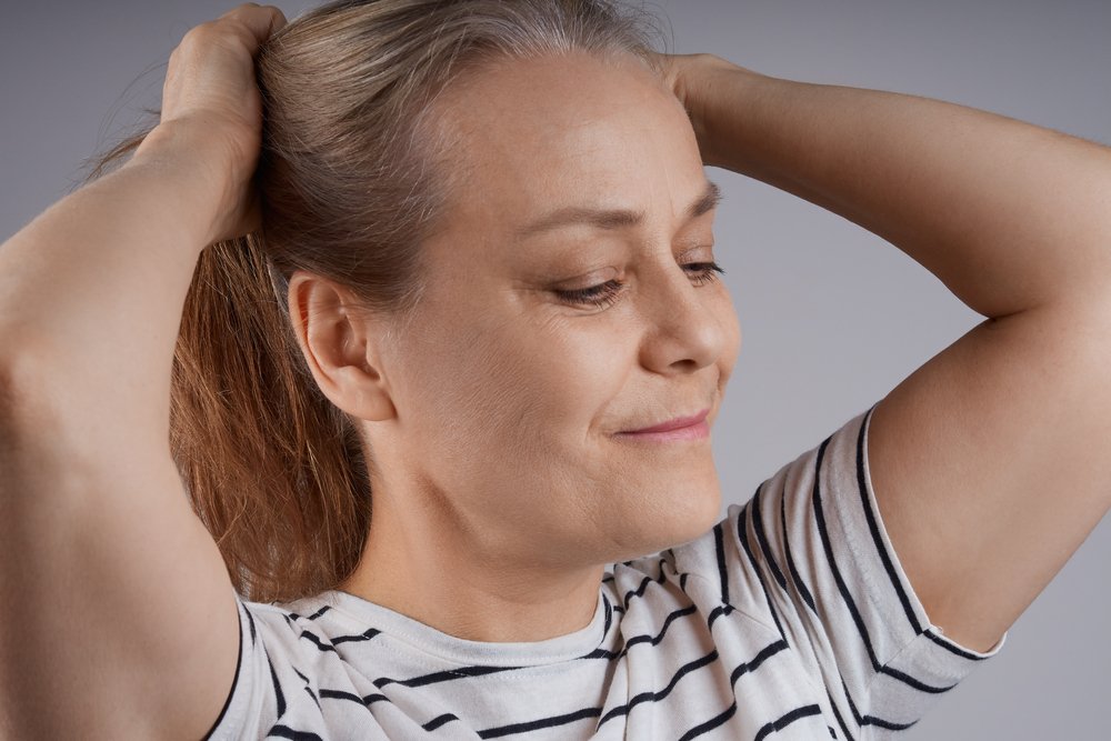Mujer amarrando su pelo en una cola de caballo. | Foto: Shutterstock