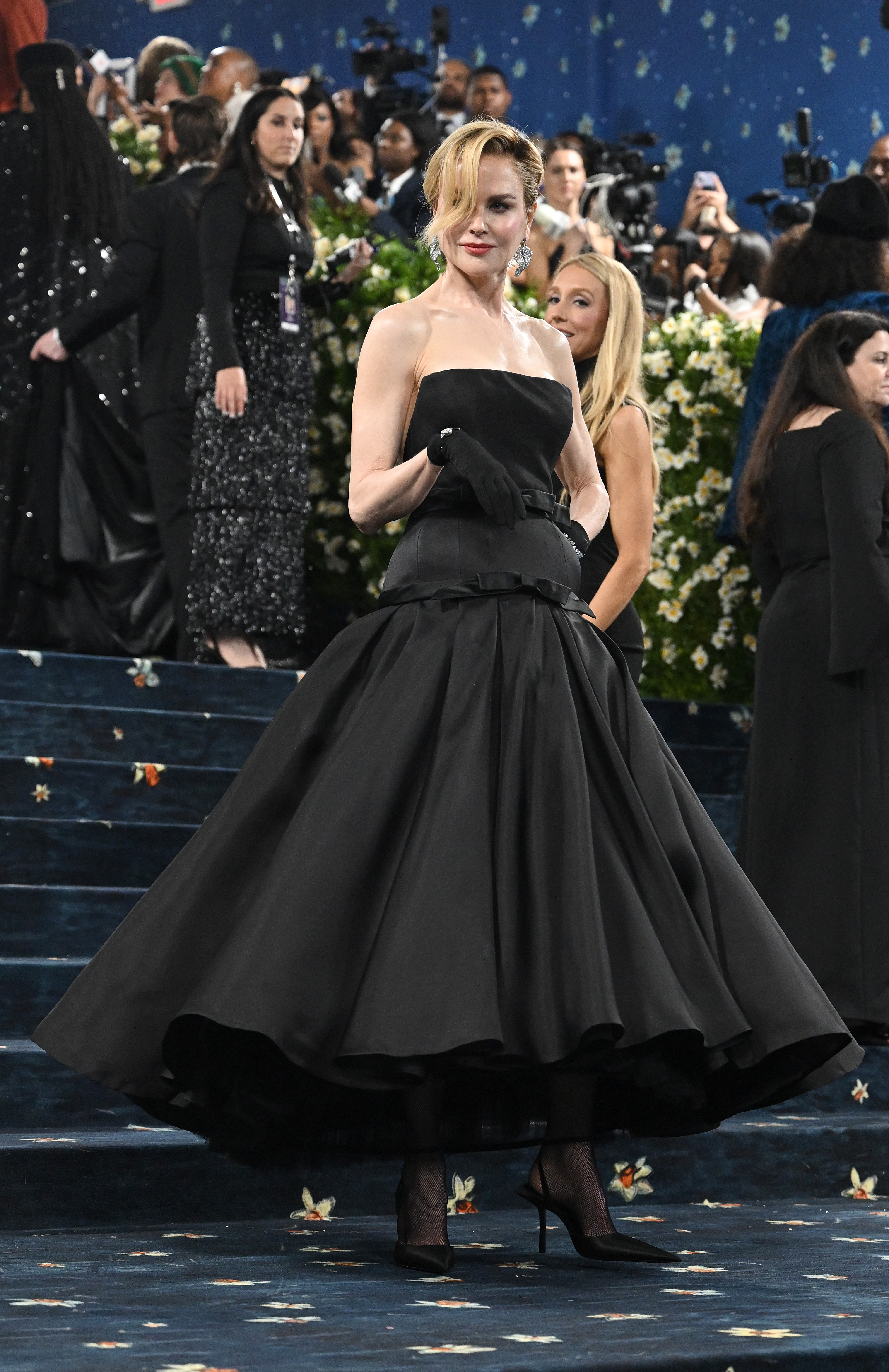 A full-body shot reveals Nicole Kidman in her custom Balenciaga gown with a dramatic silhouette. She completes the look with sleek black heels, adding a sharp finish to the couture ensemble as she stands poised beneath the Met Gala lights.