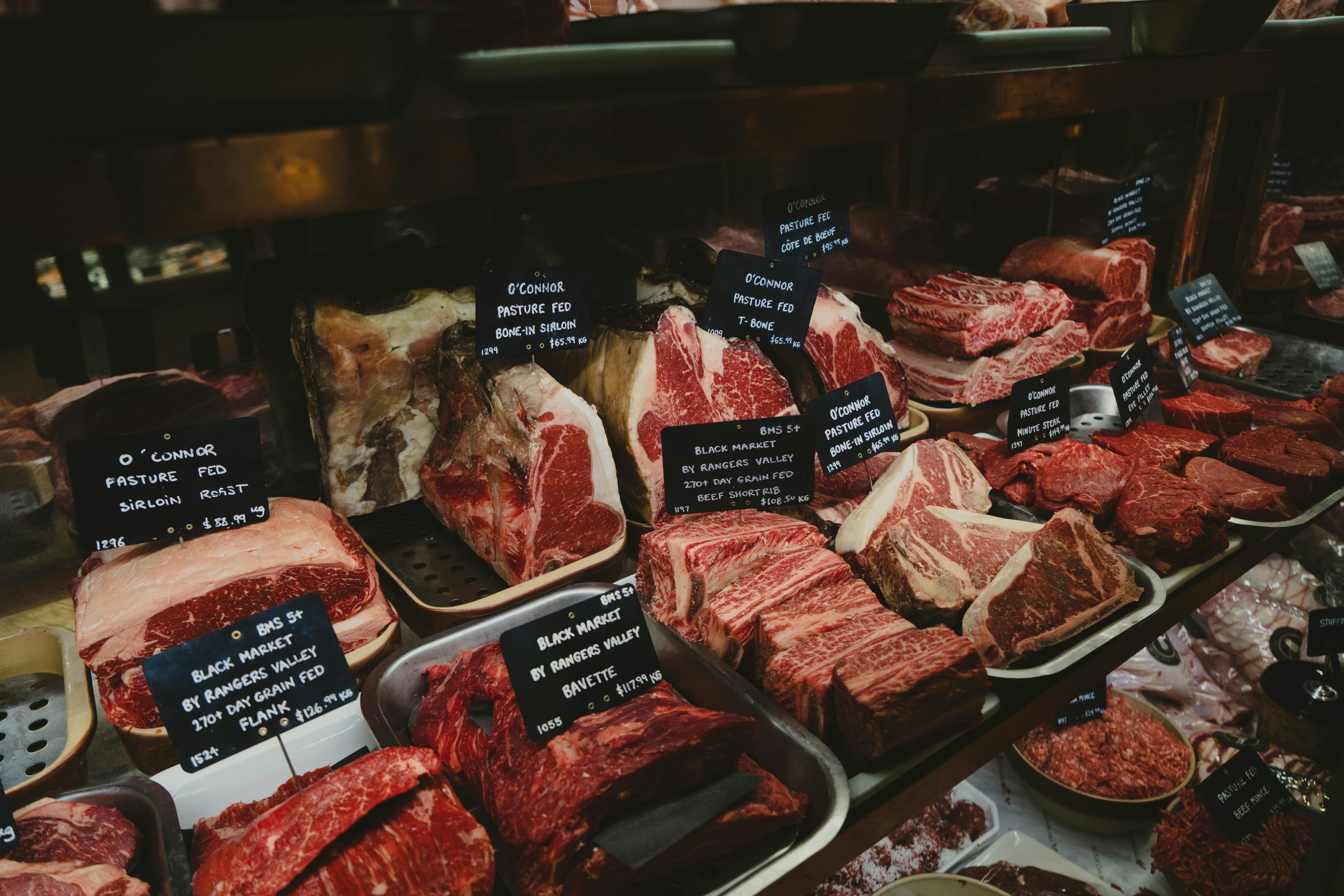 A range of raw meat cuts on display in a butcher shop. | Source: Getty Images