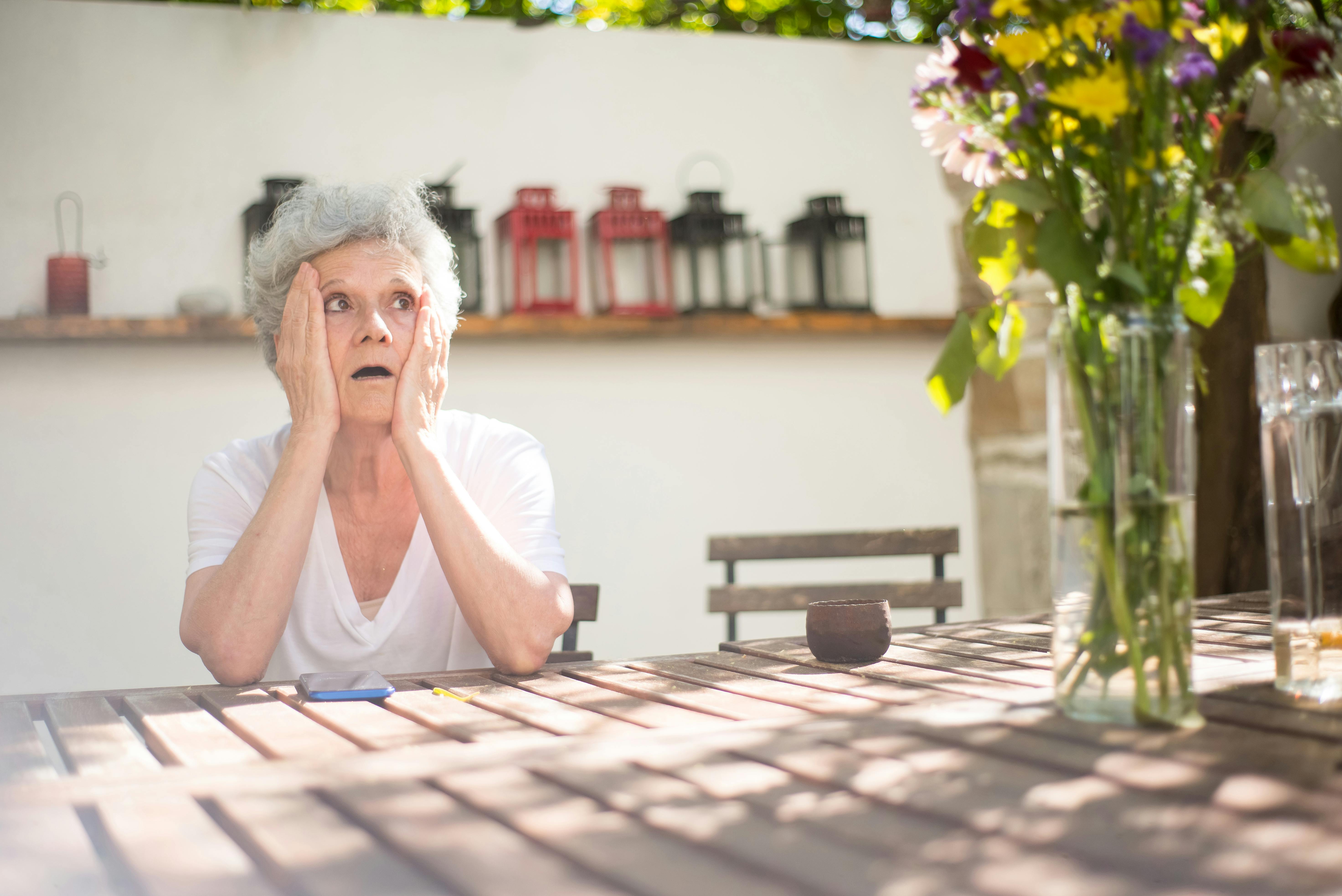 An elderly woman with her hands on her face | Source: Pexels