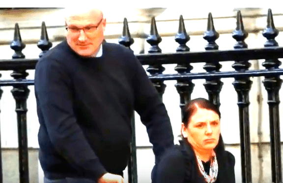 Le mari de Kerry Shaw la pousse dans un fauteuil roulant. | Source : YouTube/TV ATwood