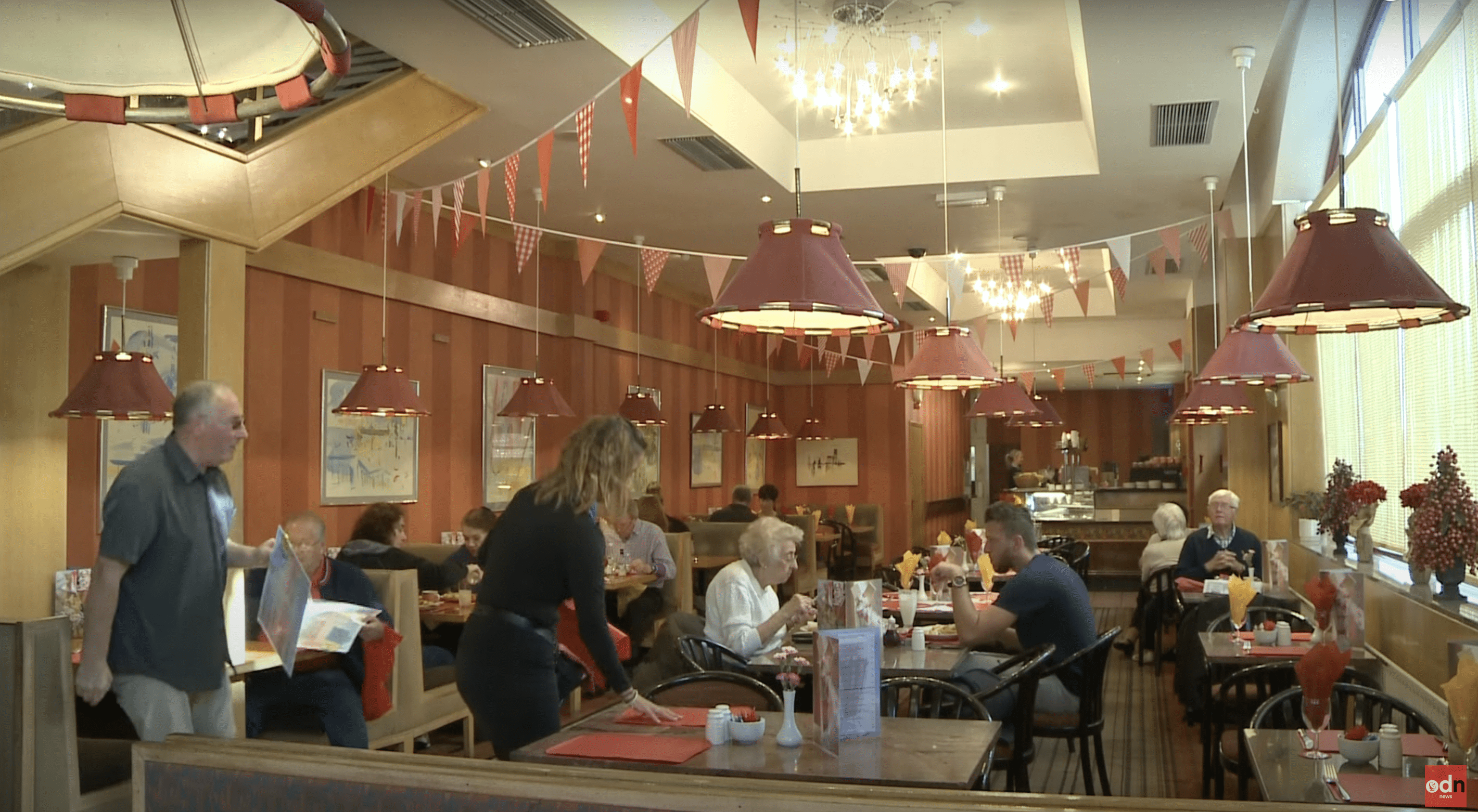 Congrave pictured setting up a table inside the cafe packed with customers. | Source: YouTube.com/On Demand News