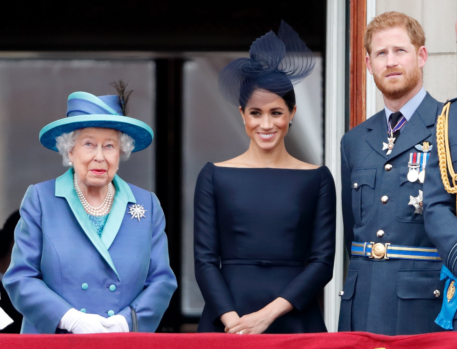 Queen Elizabeth II, Meghan, and Prince Harry watch a flypast to mark the Royal Air Force's centenary from Buckingham Palace's balcony on July 10, 2018, in London, England. | Source: Getty Images