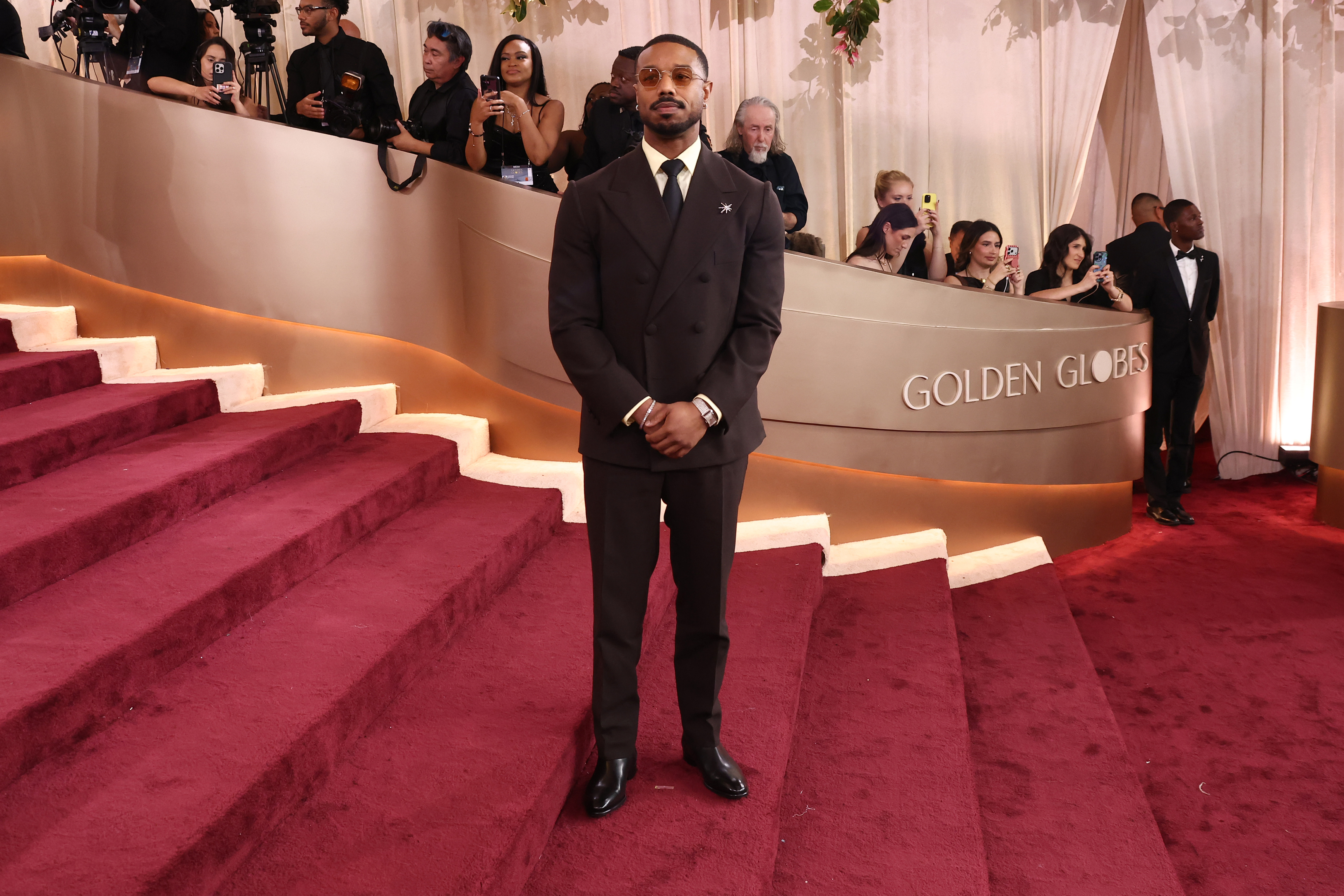 Michael B. Jordan stands at the foot of the carpeted stairs, posing with a composed stance | Source: Getty Images