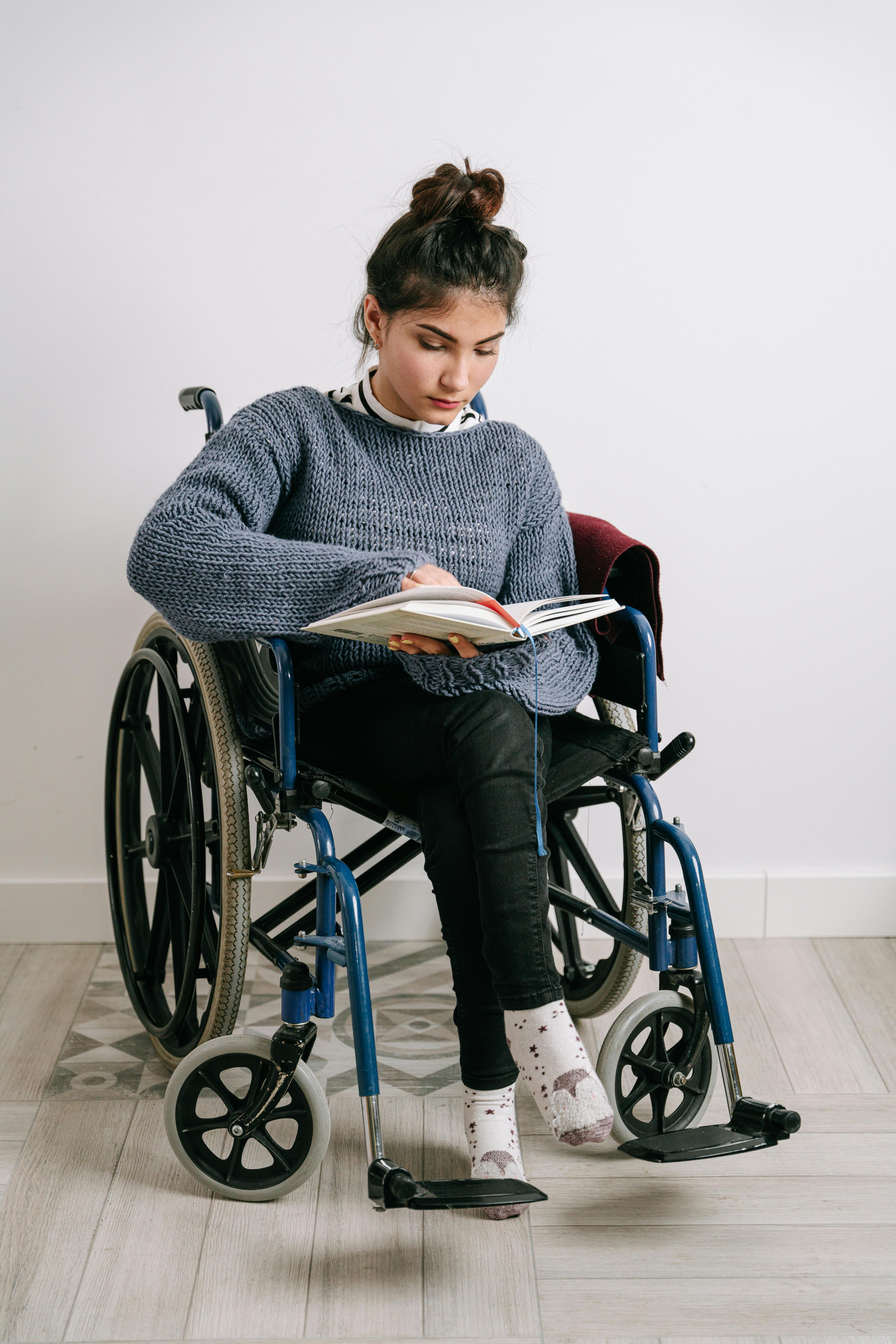 A young woman in a wheelchair reading. For illustration purposes only | Source: Pexels