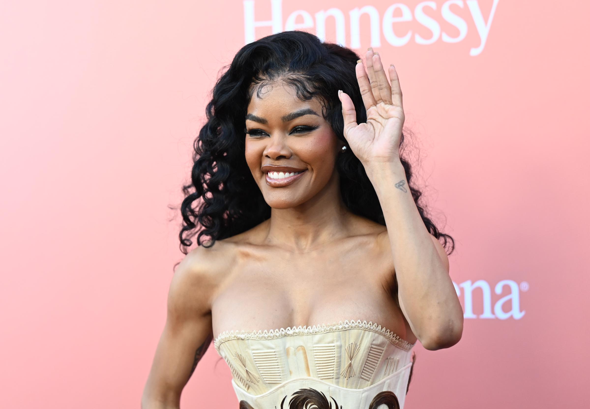 Teyana Taylor waves as she poses at the Billboard Women in Music on April 29, 2026 | Source: Getty Images