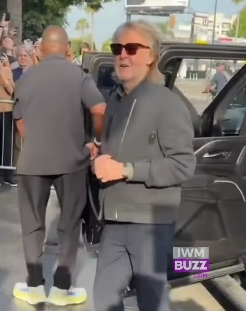 Walking forward with a slight smile, Paul McCartney held a small item in his hand as he moved away from the vehicle, his sunglasses shielding his eyes from the bright daylight. His tousled hair and beard added to the more rugged image that has recently drawn attention online. | Source: Facebook/IWMBuzz