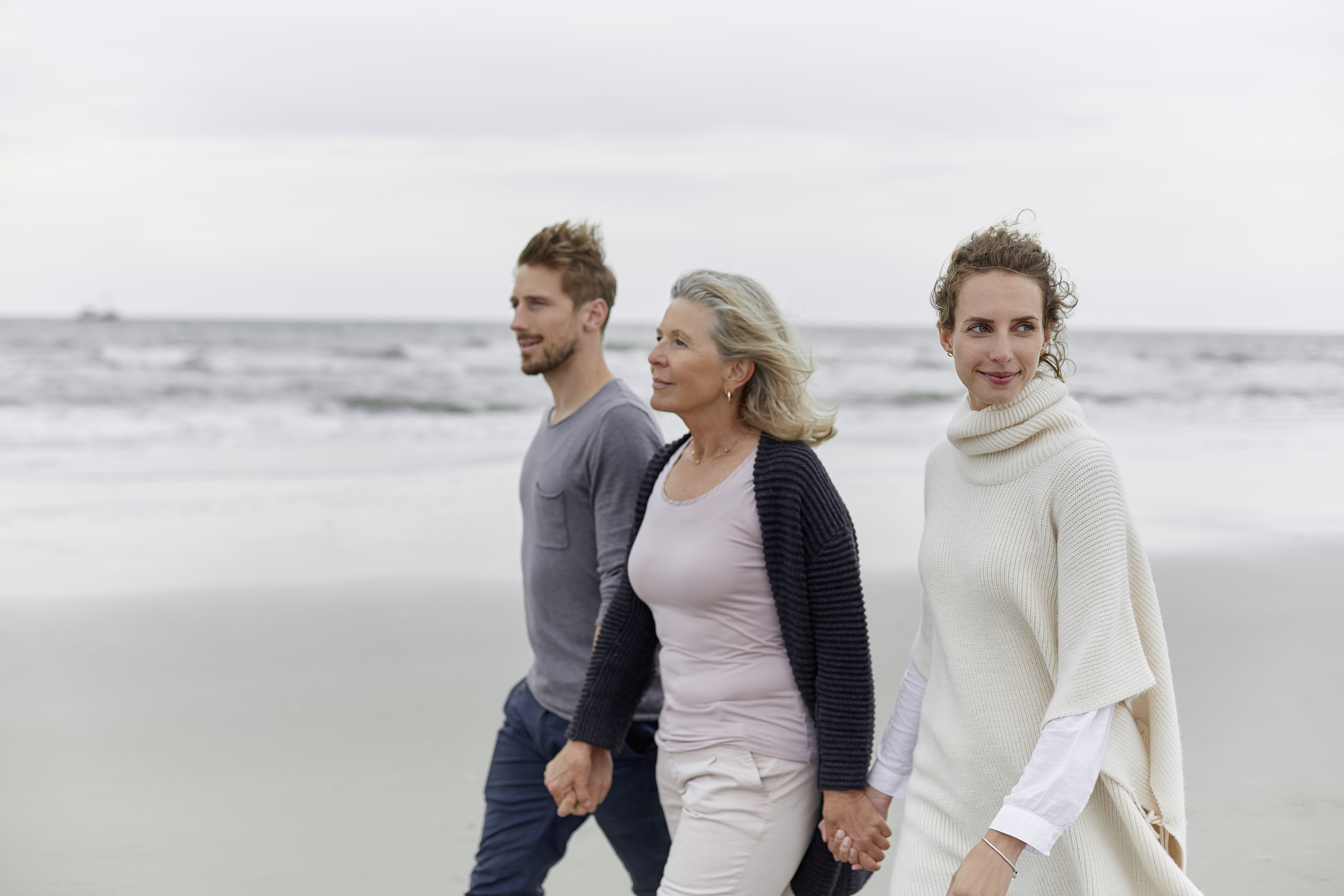 A couple walking with an older woman on a beach | Source: Getty Images