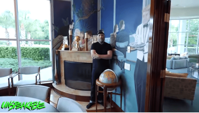 John Travolta posing in his dining room | Source: YouTube/Unspeakable