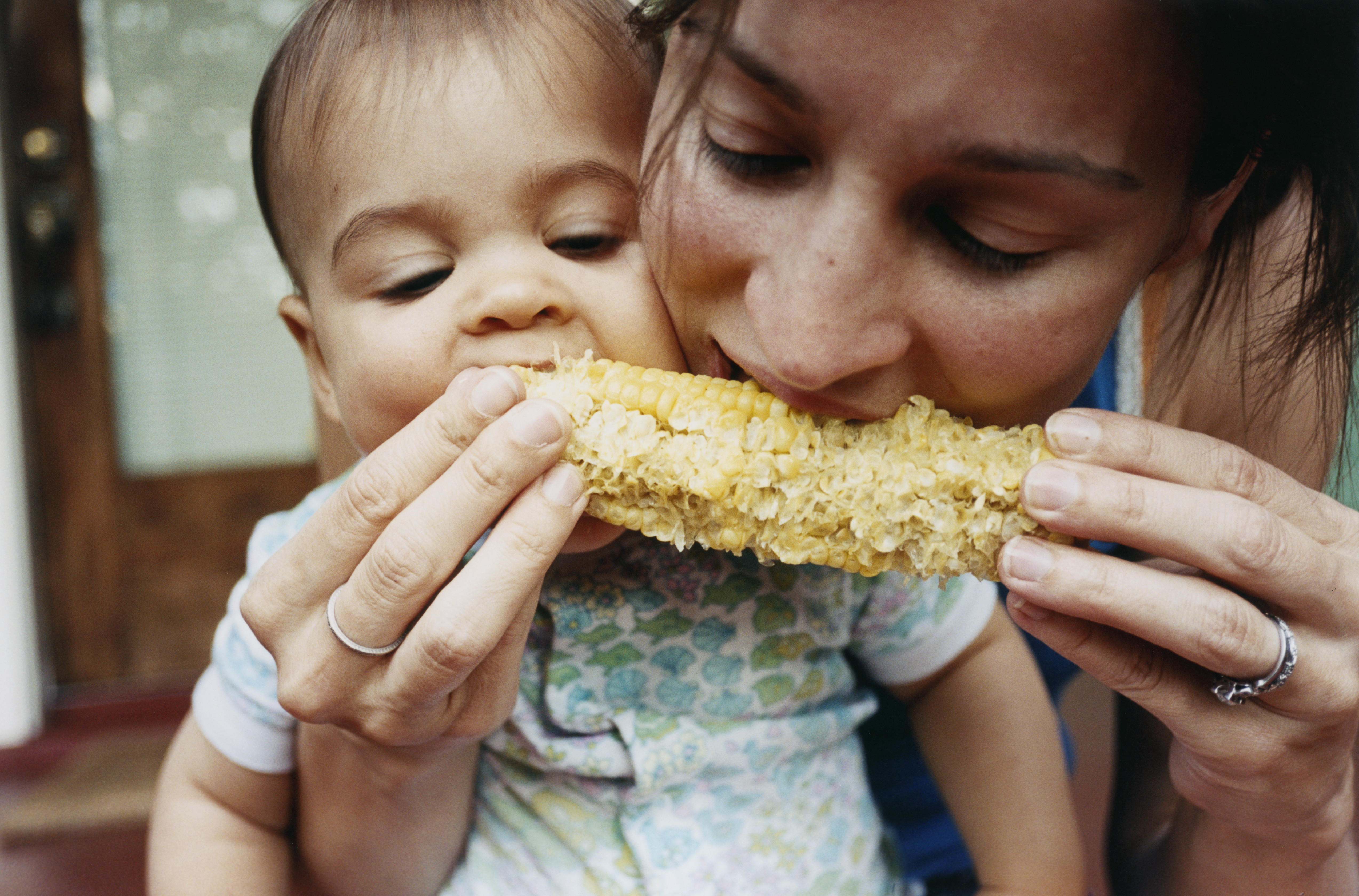 A mother and her baby eating corn | Source: Getty Images