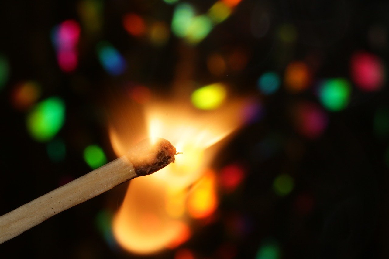 A close-up image of a flamed up match stick with a colorful background | Photo: Pixabay/markito