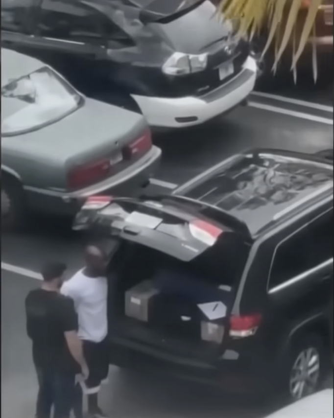 Stephen Bowen and the other man stand near the open trunk of a dark SUV in a parking lot, where boxes are visible inside, suggesting evidence collection or investigative activity. | Source: YouTube/WPLG Local 10
