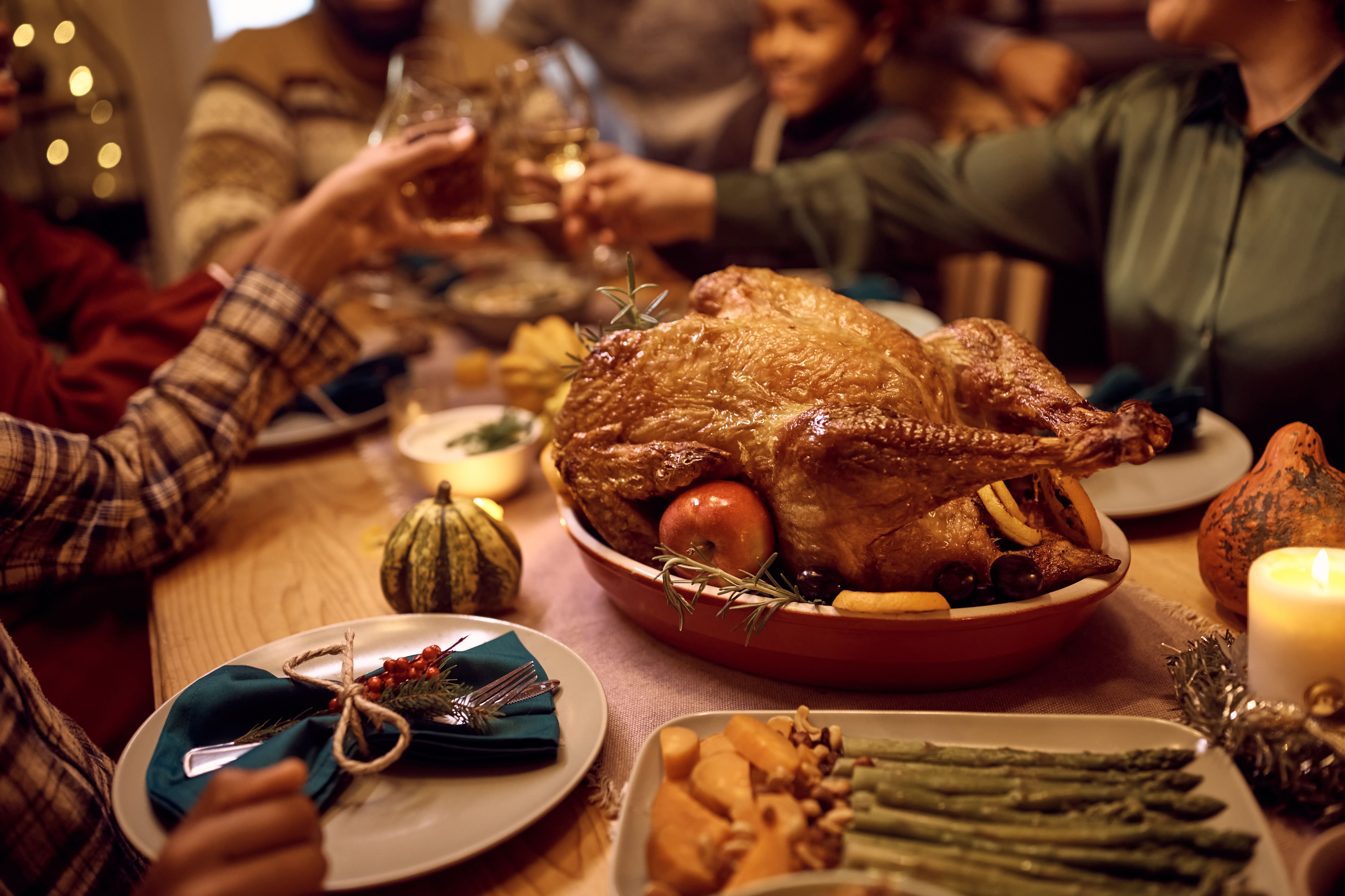 A roast turkey sitting on a table while people make a toast. | Source: Getty Images