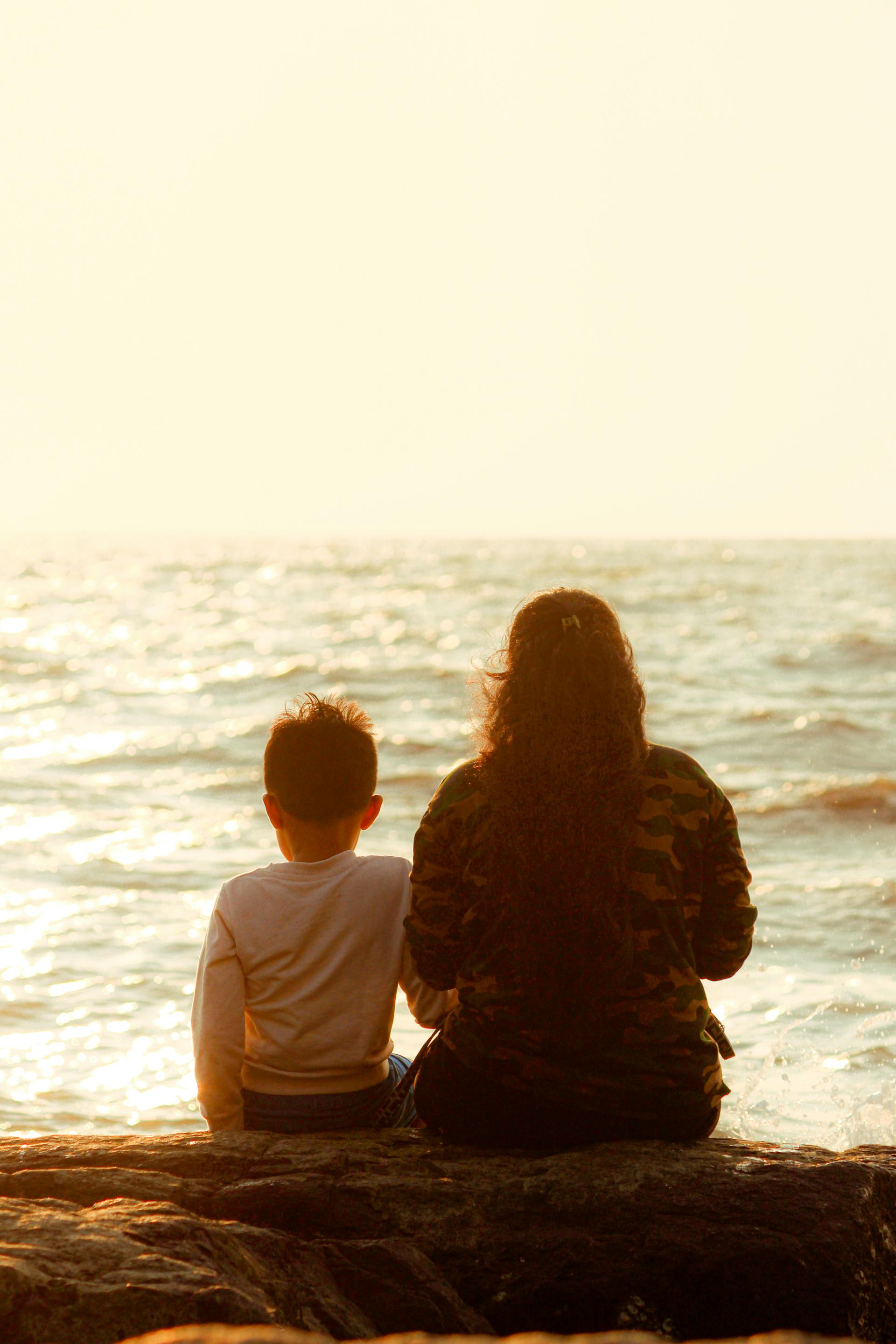 A mother sitting with her son on the seashore | Source: Pexels