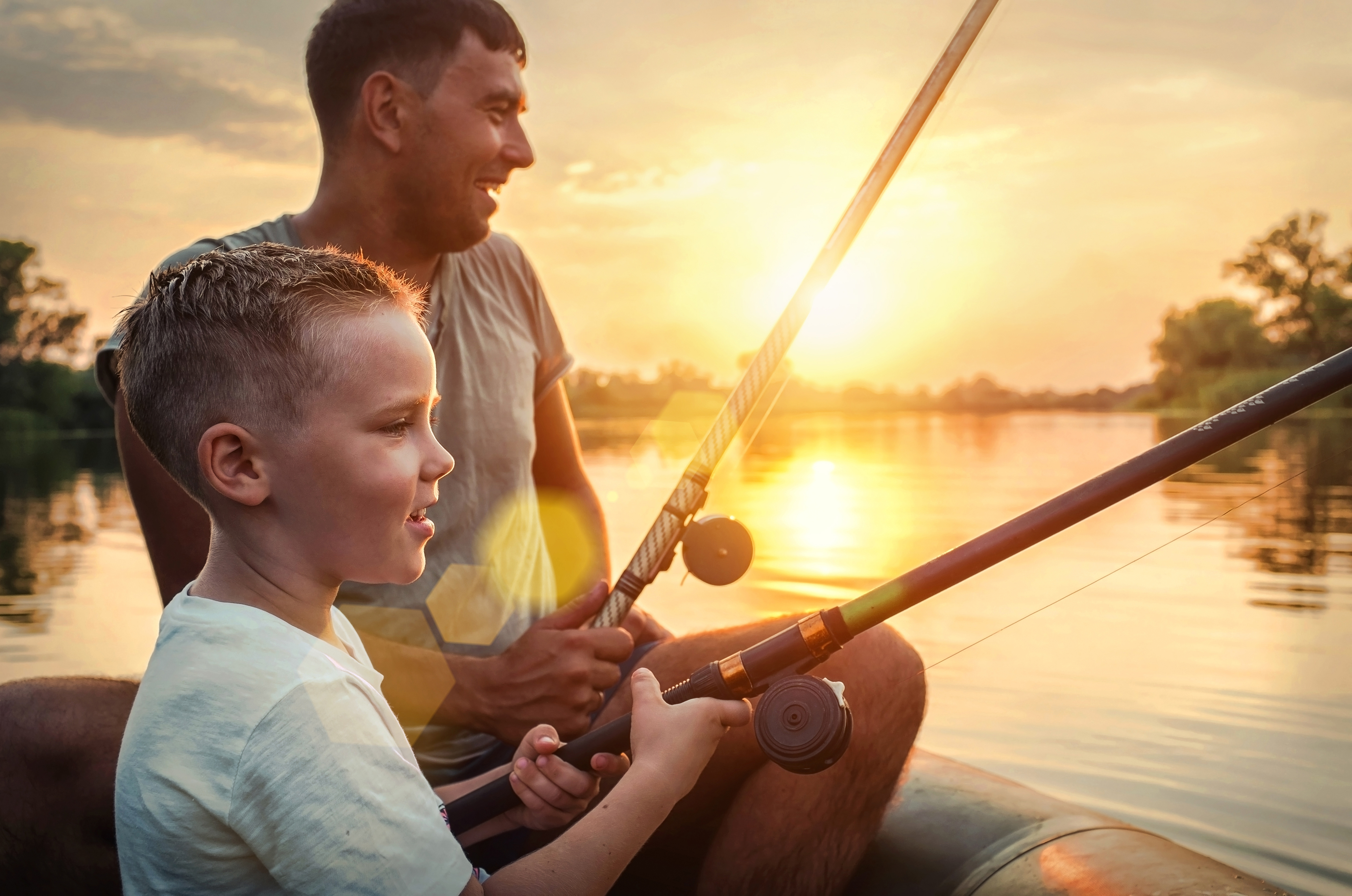 Father and son fishing together from a boat during sunset | Source: Shutterstock