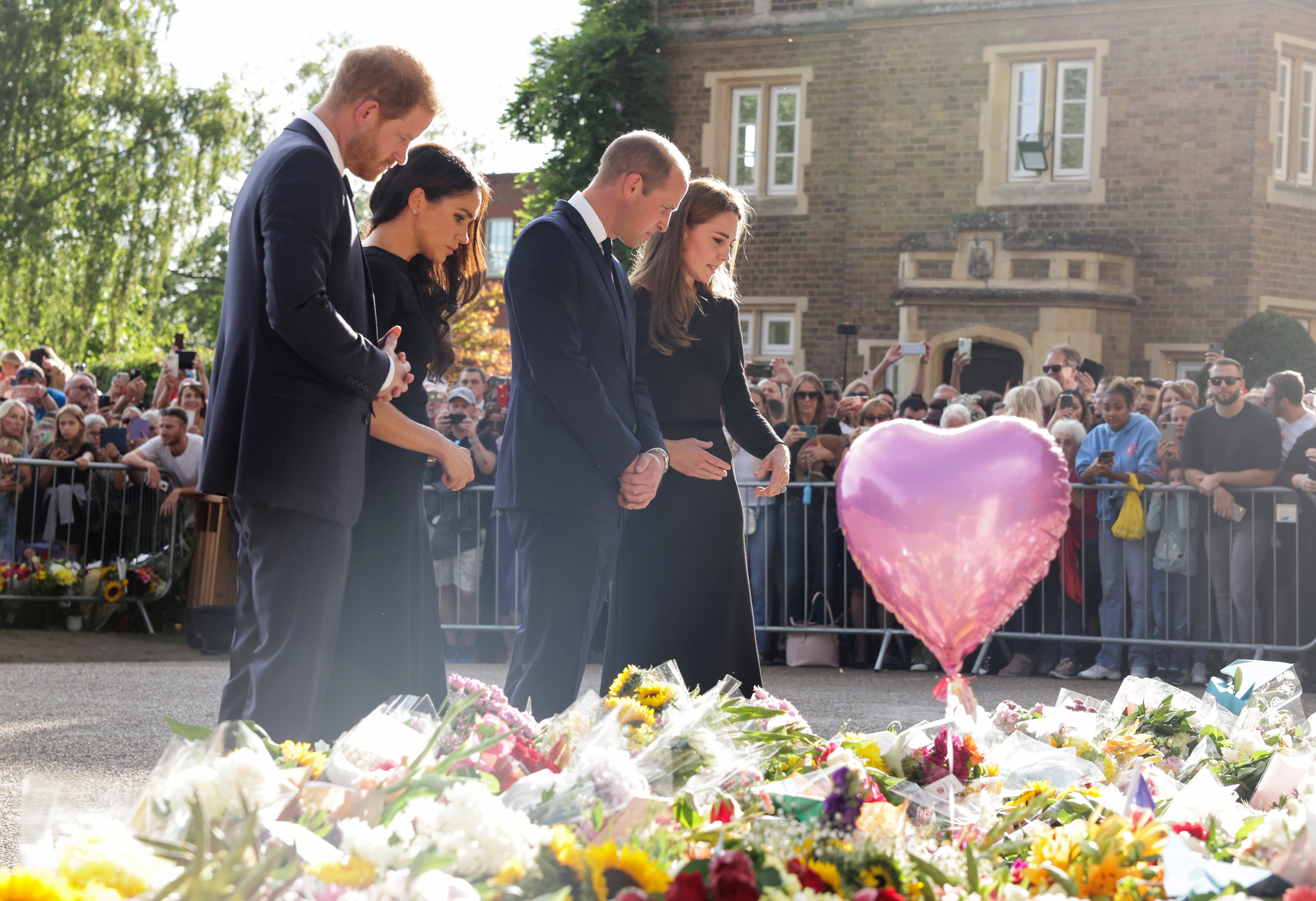 Prince Harry, Duke of Sussex, Meghan, Duchess of Sussex, Prince William, Prince of Wales, and Catherine, Princess of Wales look at floral tributes laid by members of the public on the Long Walk at Windsor Castle on September 10, 2022, in Windsor, England. | Source: Getty Images