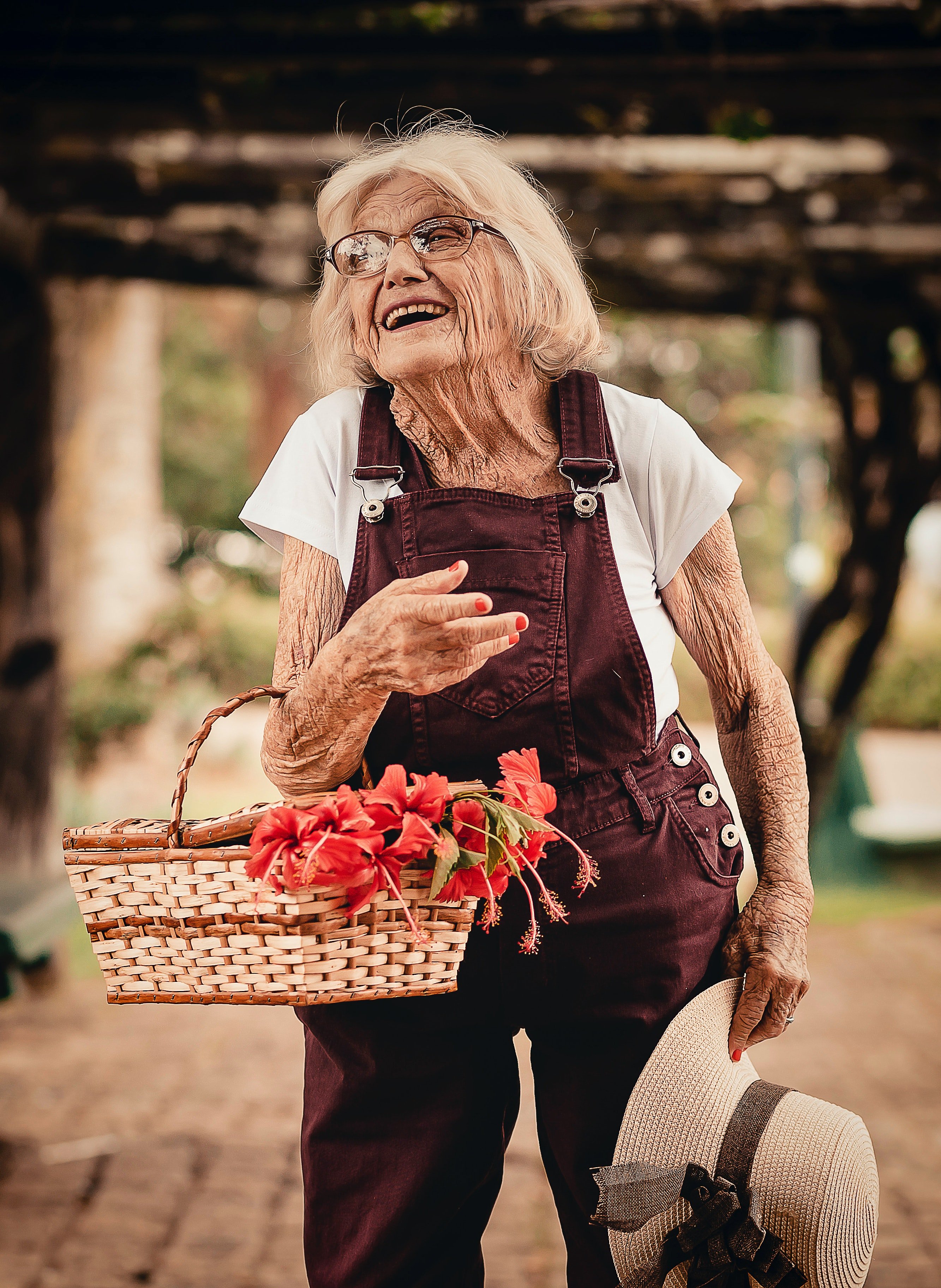 Una anciana con una cesta llena de flores en su brazo. | Foto: Pexels