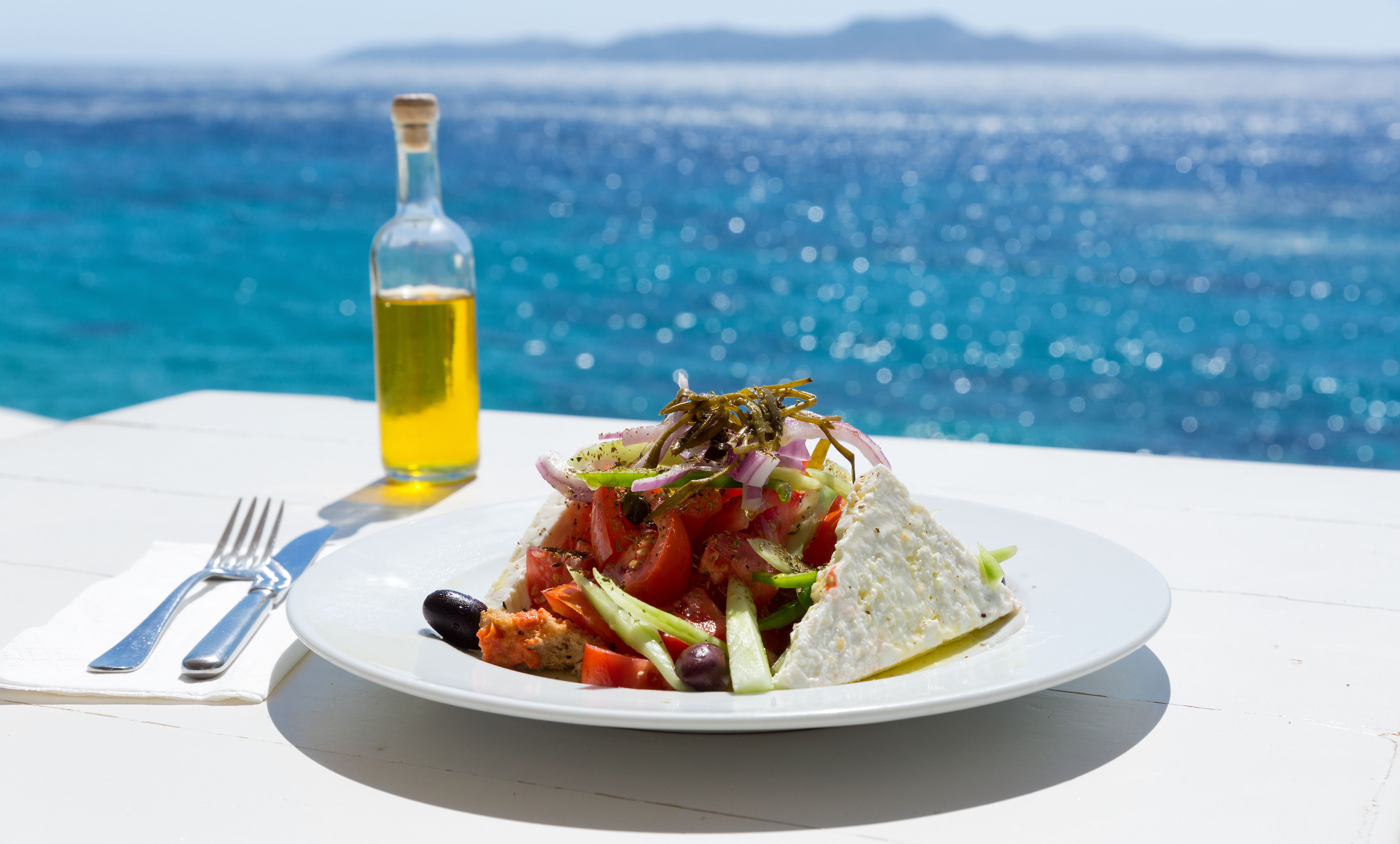 Seafood salad and olive oil by the ocean. | Source: Shutterstock