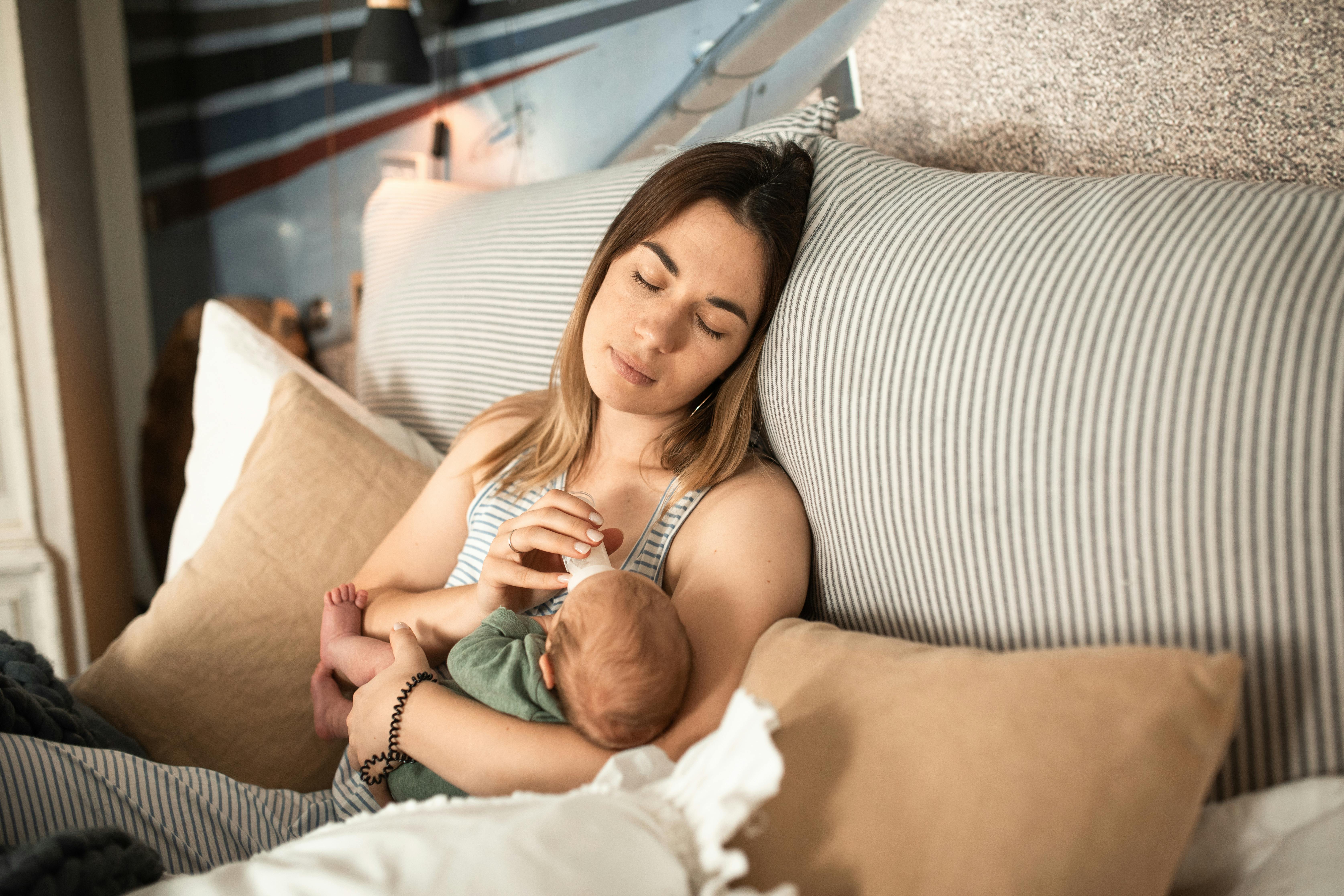 An exhausted woman feeding a newborn baby | Source: Pexels