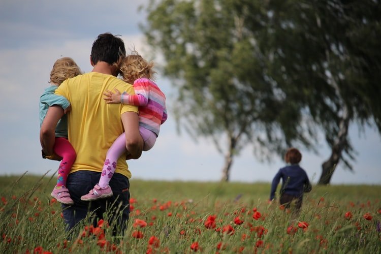 Un père qui porte ses enfants dans ses bras. | Photo : Unsplash Un père qui porte ses enfants dans ses bras. | Photo : Unsplash
