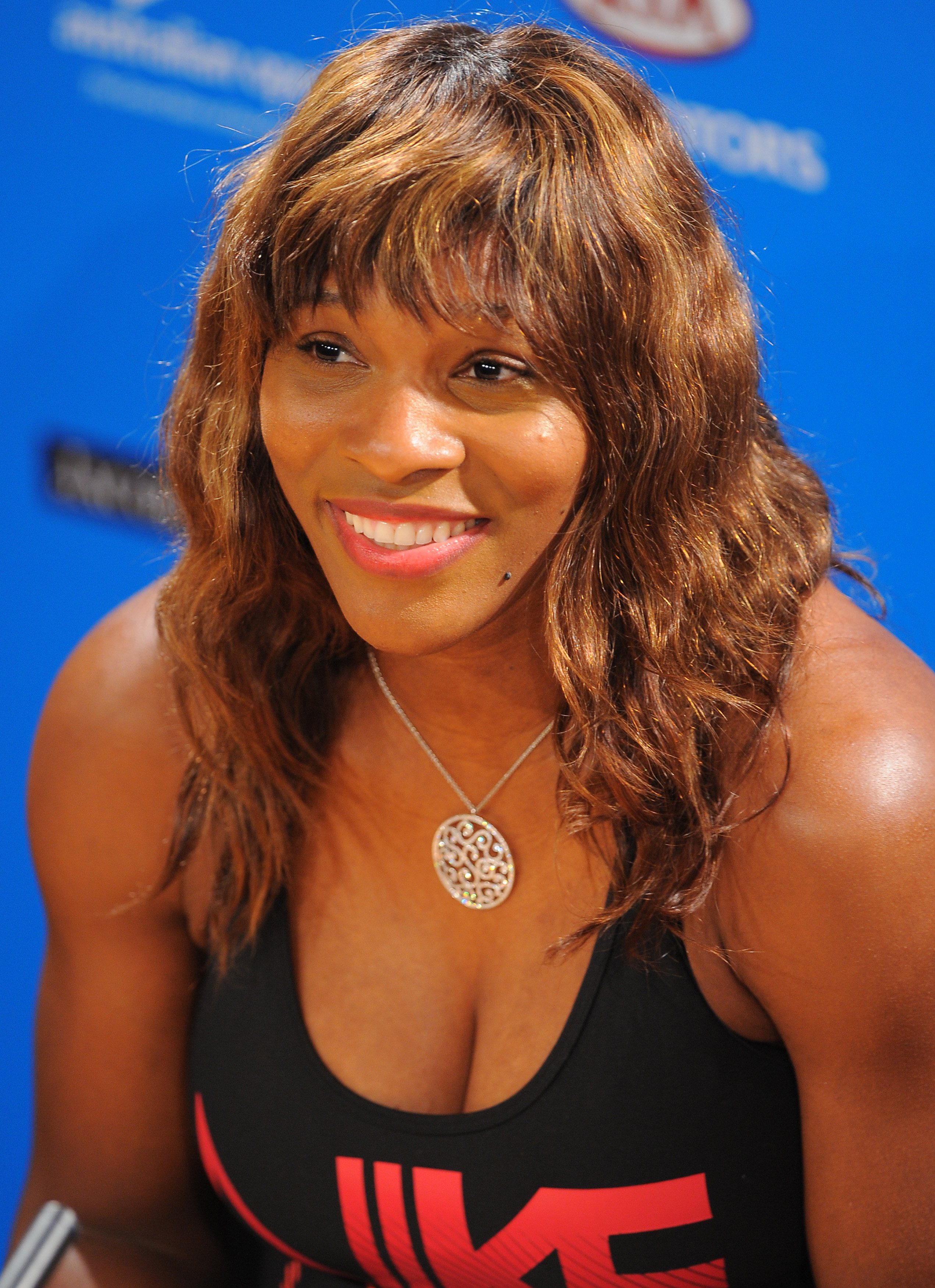 At a press event during the Australian Open in January 2010, Serena Williams addressed reporters as the defending champion. She wore a simple black outfit and a silver cross necklace, her hair styled in soft curls.