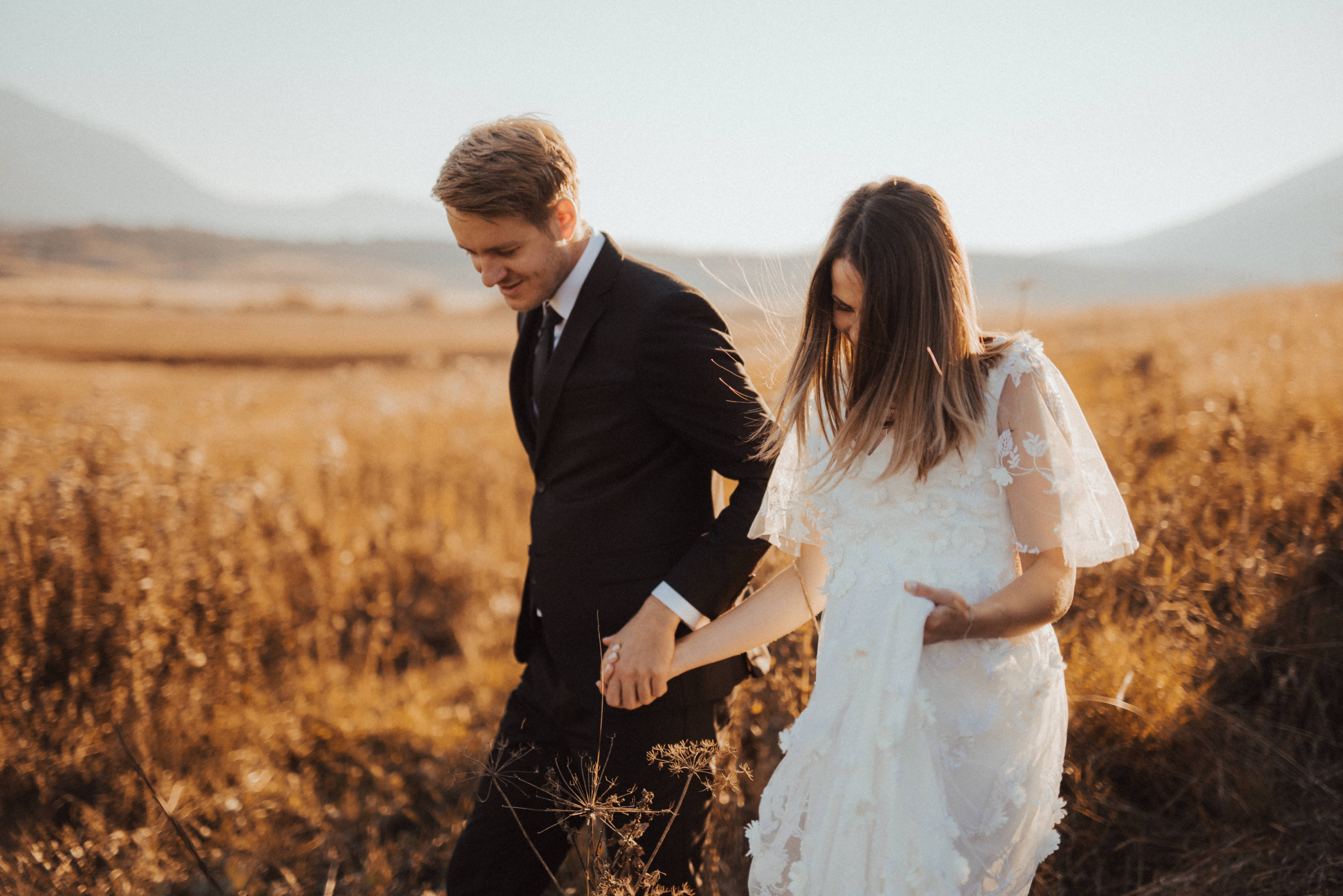 A bride and groom walking through a field. | Source: Pexels