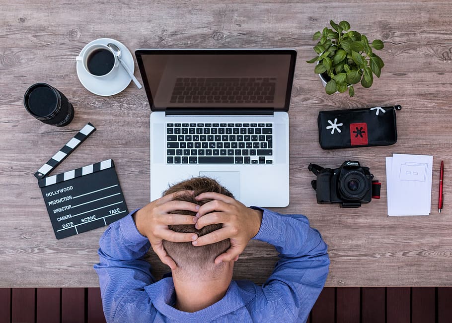 Hombre en su escritorio frente a su laptop sosteniendo su cabeza. | Foto: PxFuel