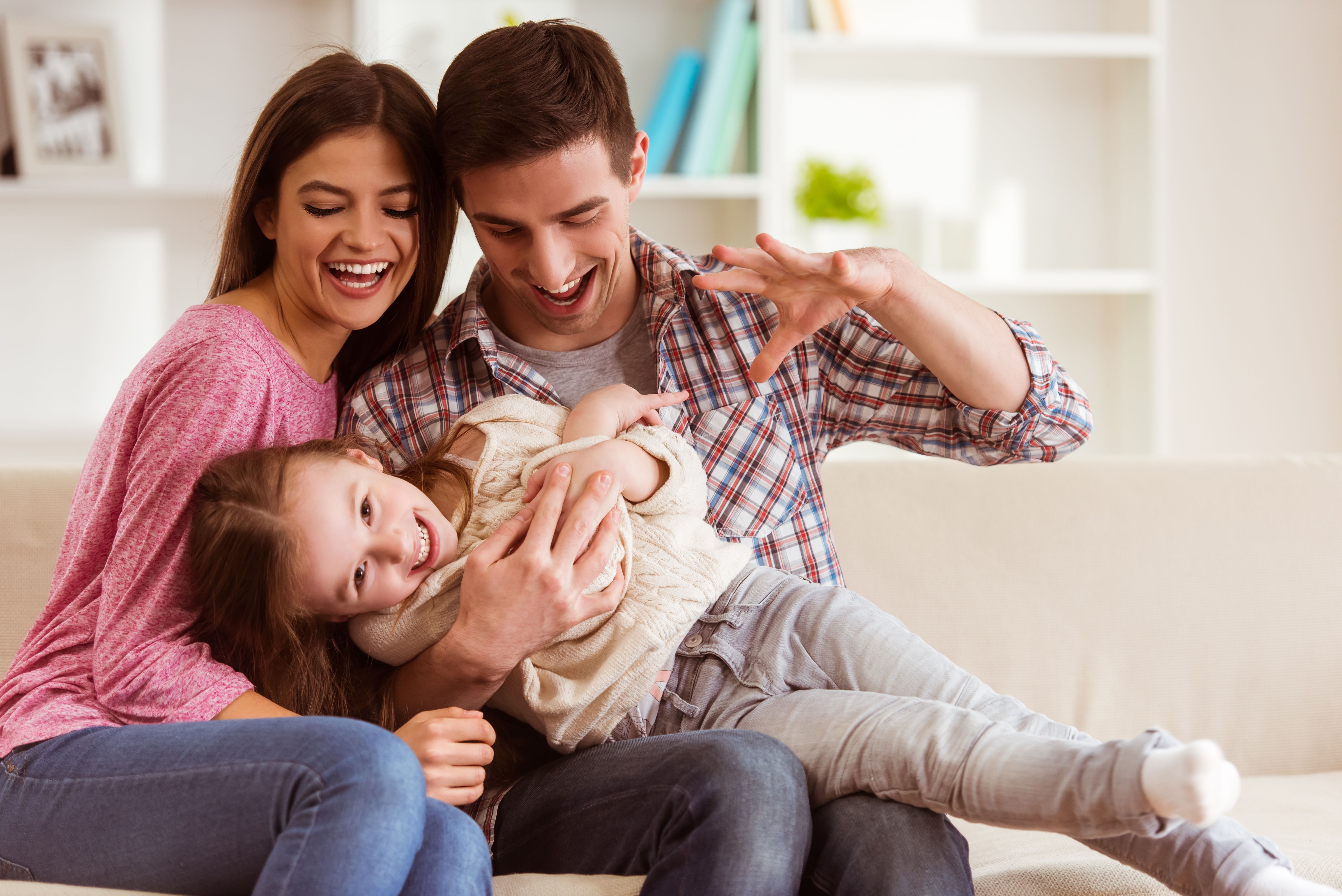 Smiling young parents and their child playing together at home | Photo: Shutterstock/VGstockstudio