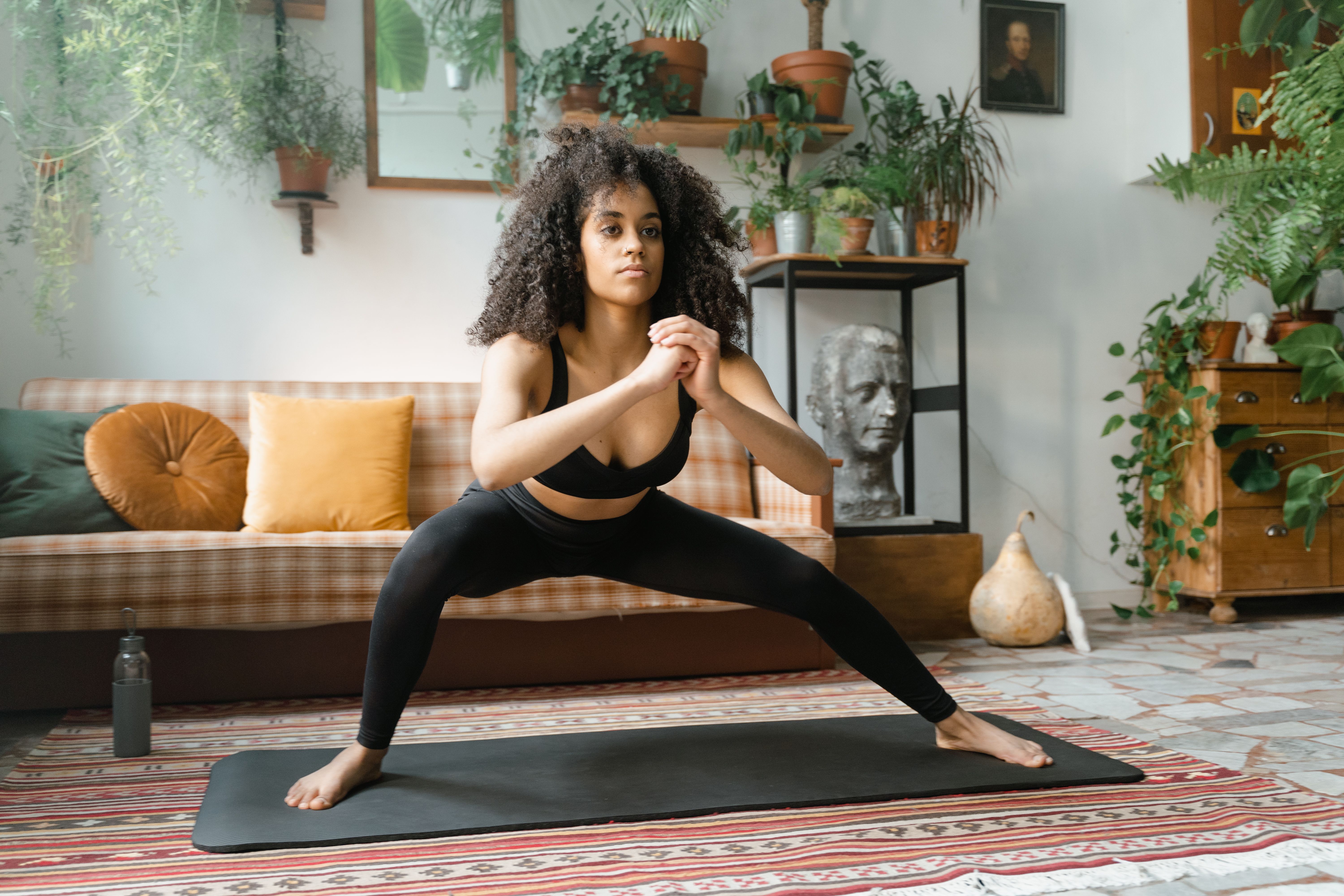 A woman performs a squat exercise on a yoga mat at home. | Source: Pexels