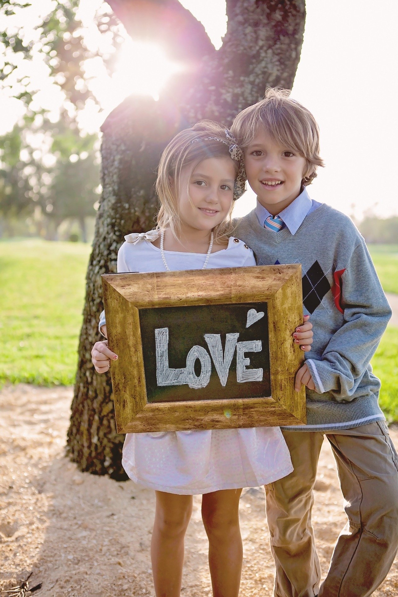 A photo of siblings holding a love frame. | Photo: Pixabay