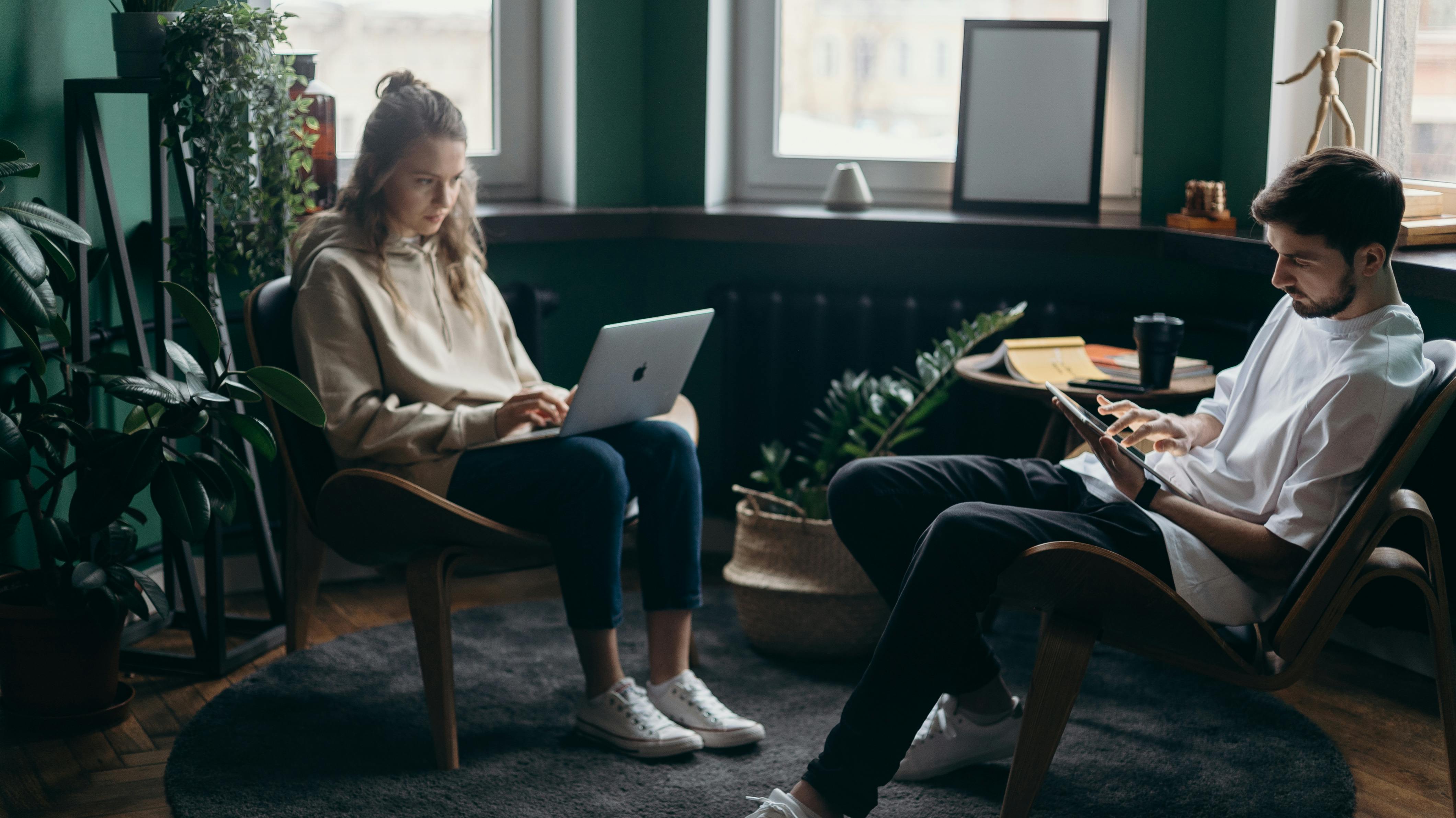 A woman doing research on her laptop as her husband does research on his phone | Source: Pexels