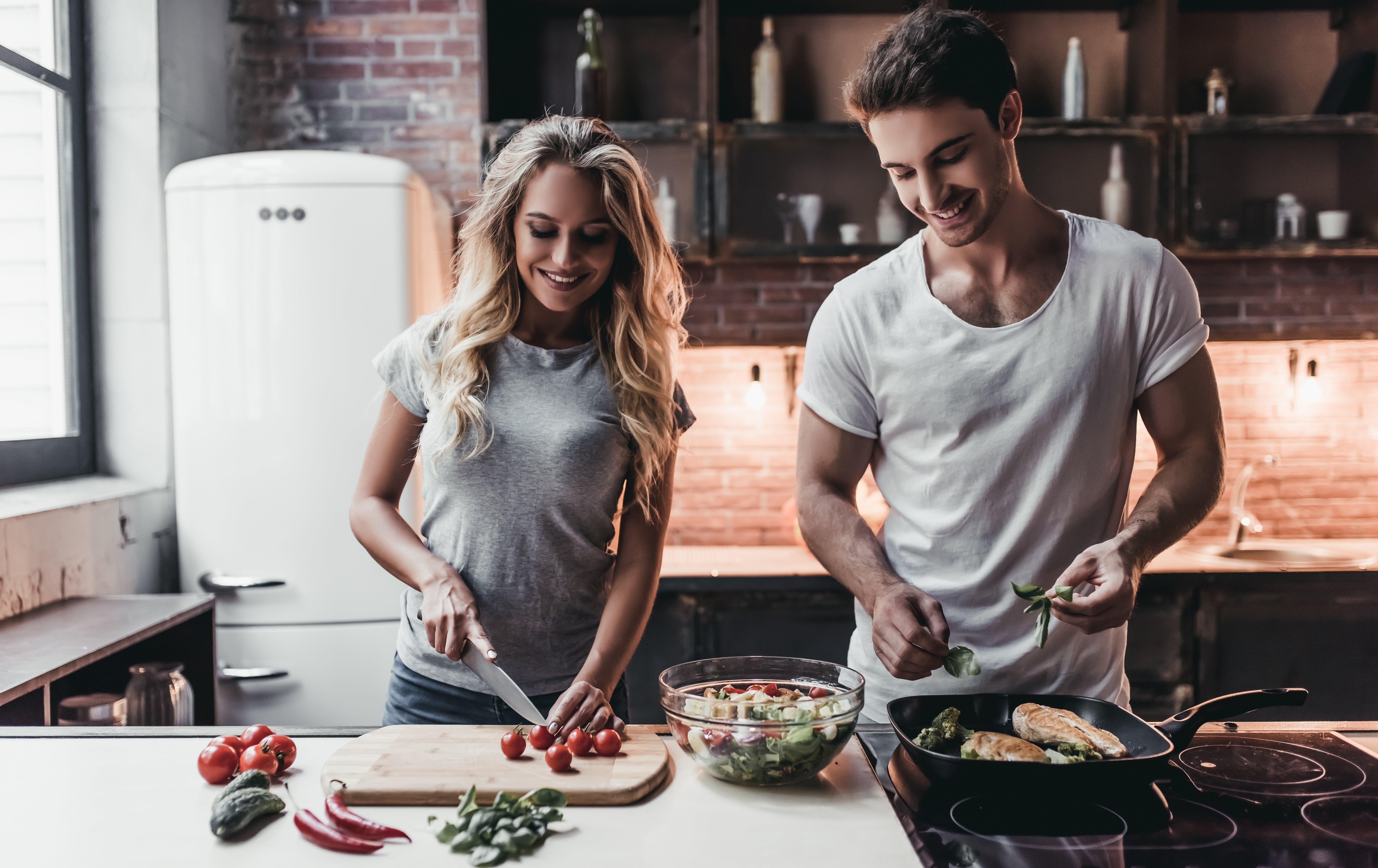Happy couple preparing food in the kitchen. | Source: Shutterstock.com