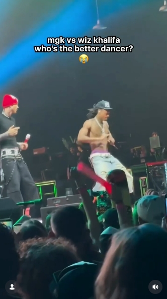 Wiz Khalifa takes center stage as he shows off a series of dance moves while MGK watches from the side during their impromptu dance-off at Truliant Amphitheater. The crowd can be seen raising phones and glow sticks as the performance unfolds. | Source: Instagram/mgkmagic