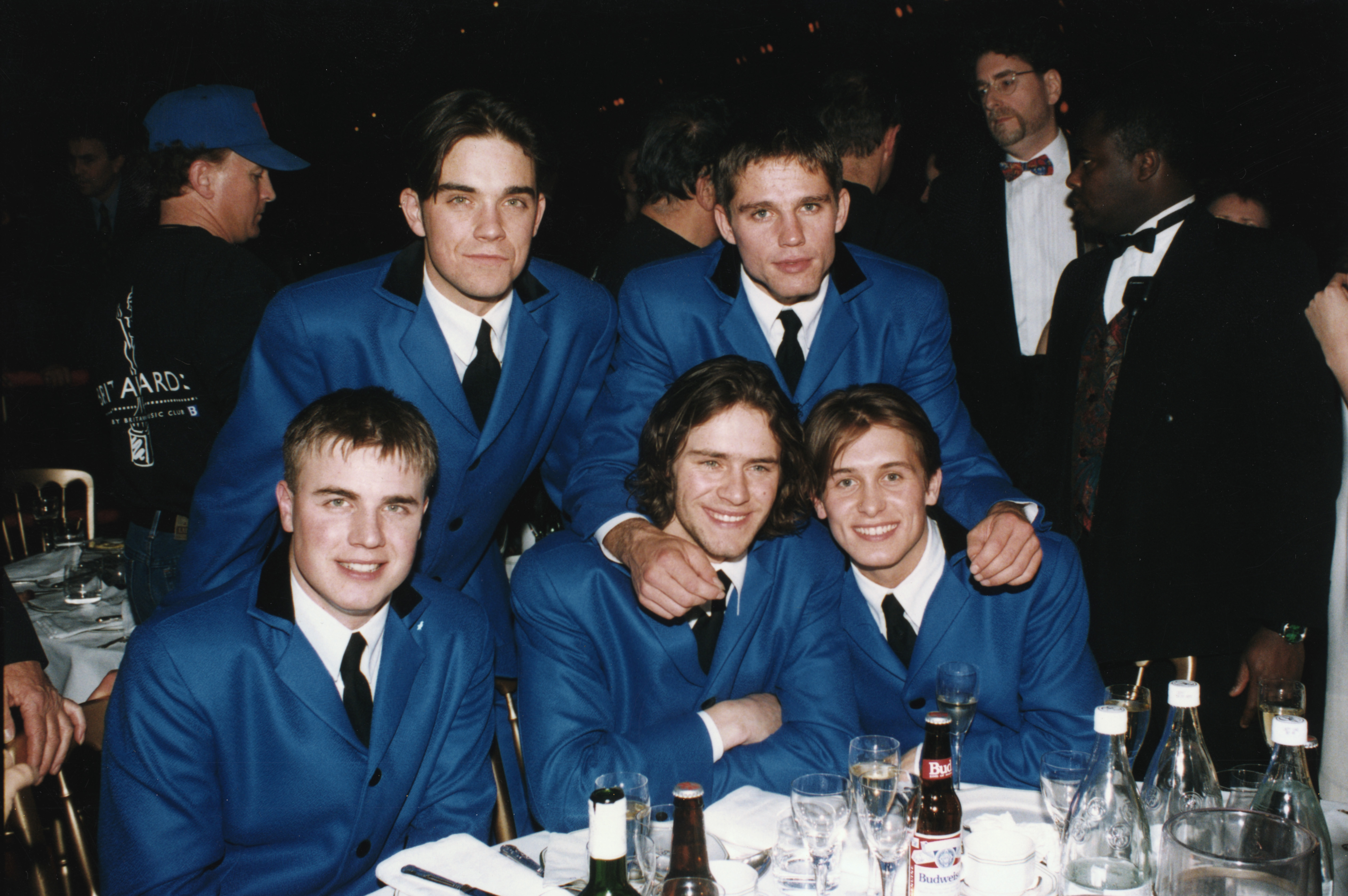 Robbie Williams and his Take That bandmates attend the Brit Awards in 1994, dressed in matching electric-blue suits. At the height of their fame, the group dominated the UK charts — and their polished look here matched the pop powerhouse they had become.