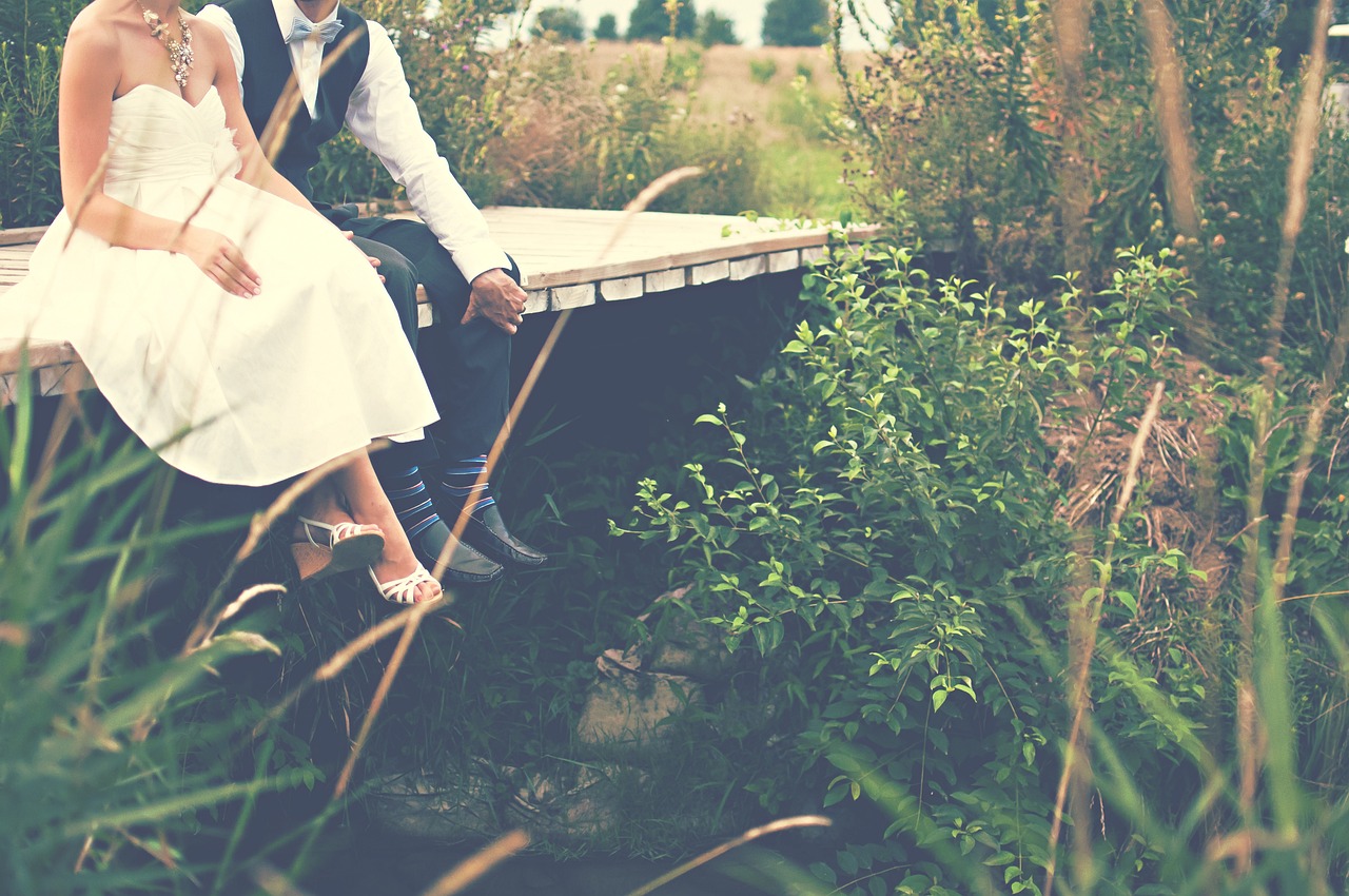 Bride and groom sitting on a bridge | Source: Pixabay