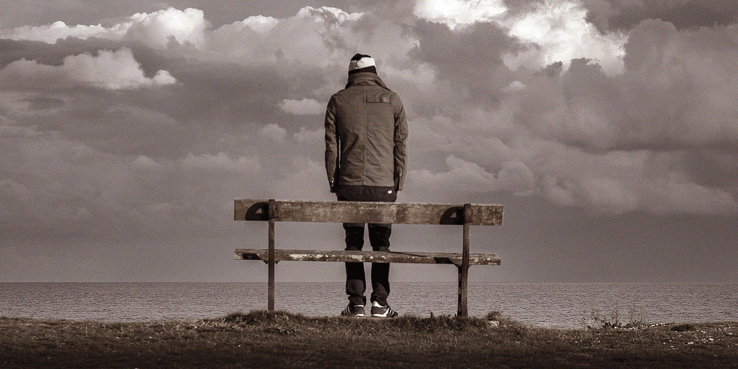 A man standing in front of a bench while overlooking the ocean | Source: Unsplash