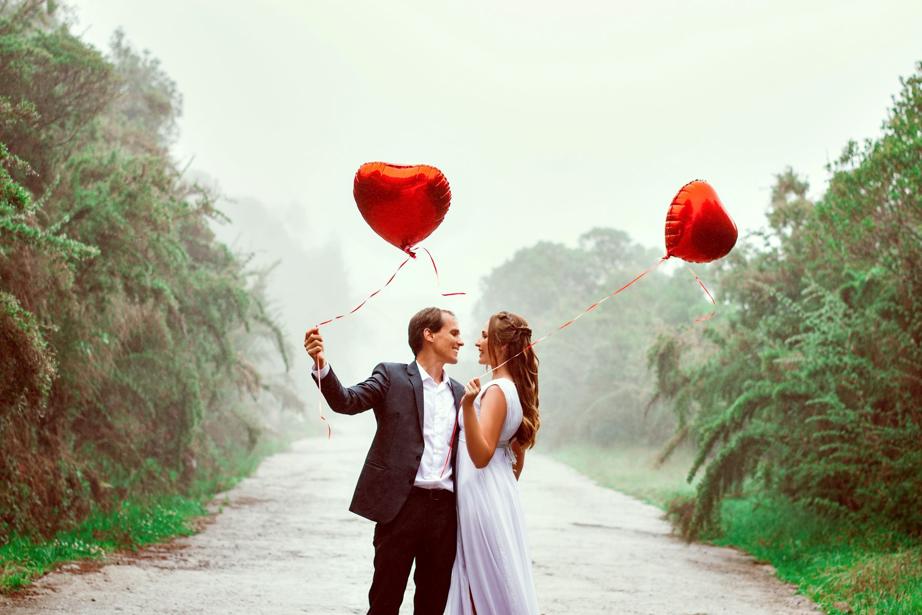 A couple getting married while holding red heart balloons in their hands. | Source: Pexels