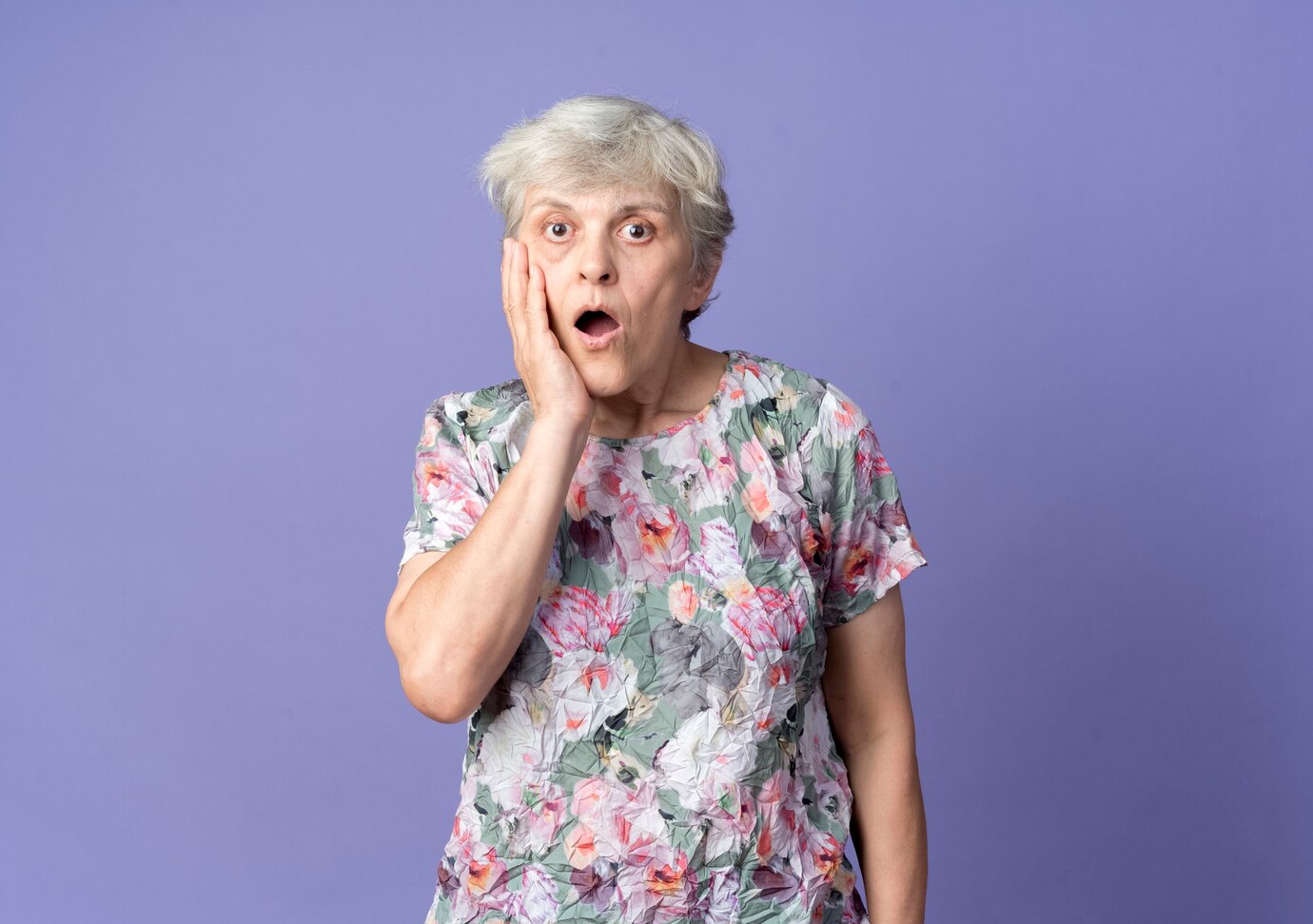 Een geschrokken oudere vrouw raakt haar gezicht aan | Bron: Freepik