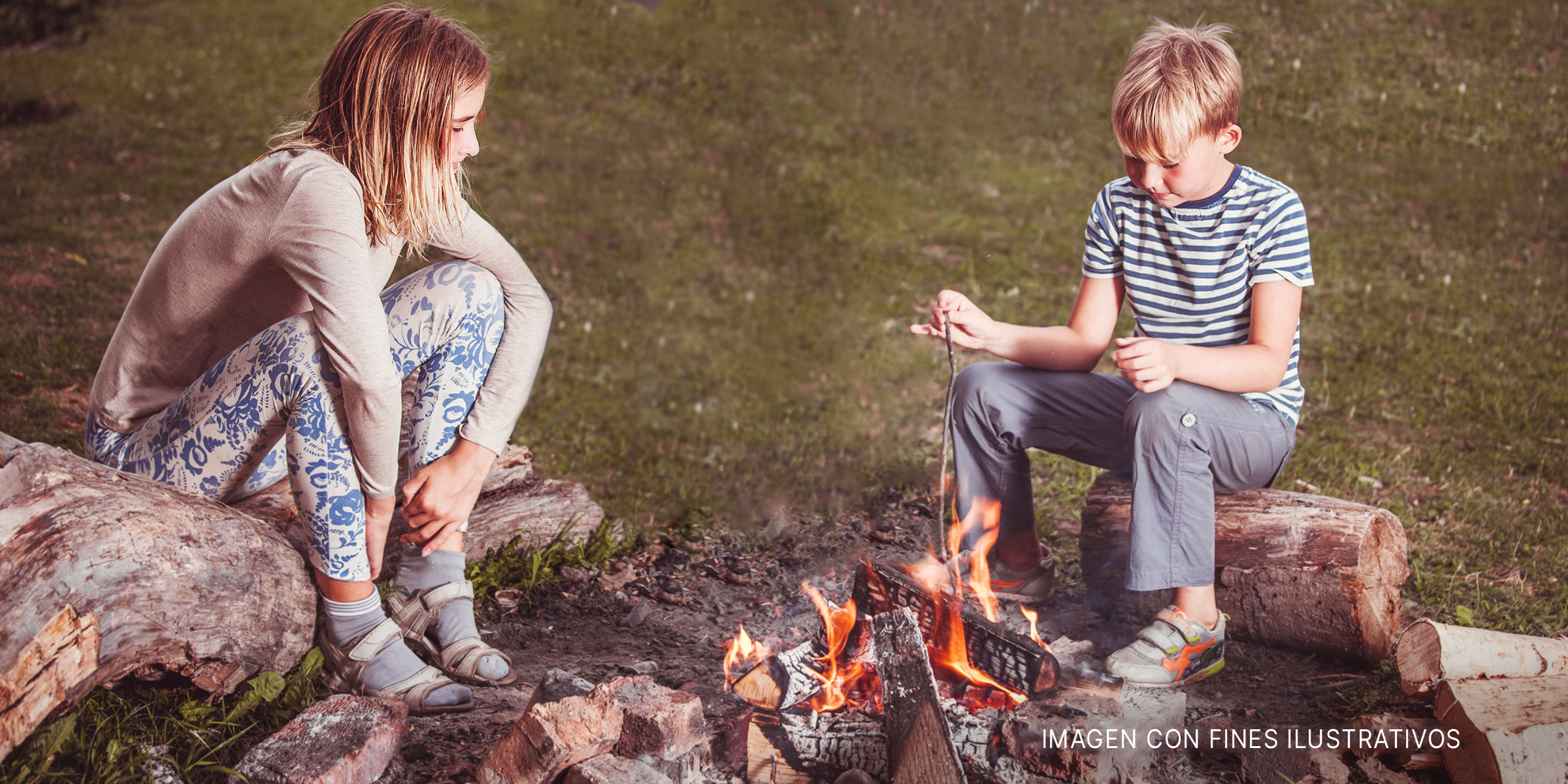 Un niño y una niña sentados frente a una fogata. | Foto: Shutterstock