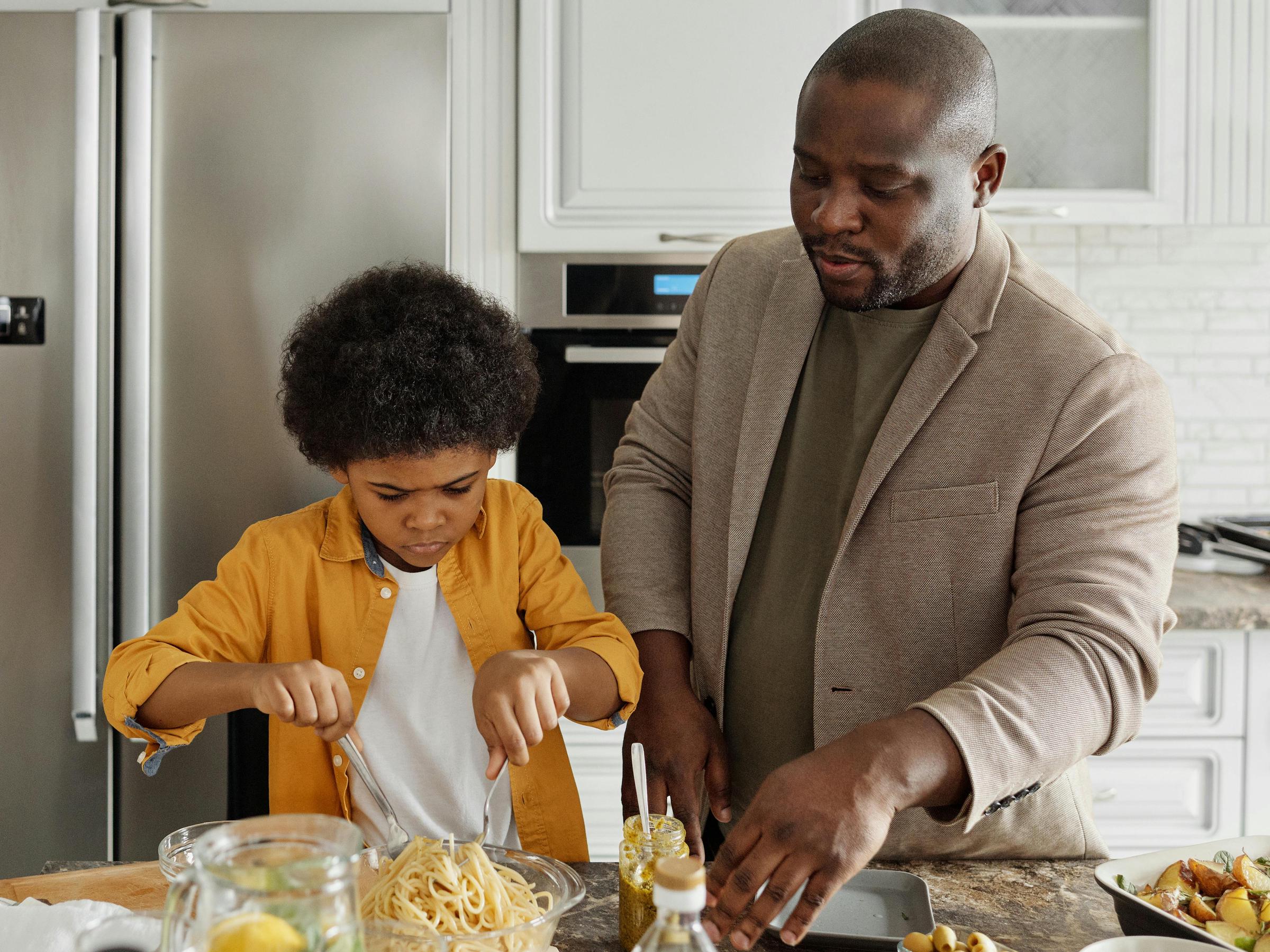 A man helping a child dish up a meal | Source: Pexels