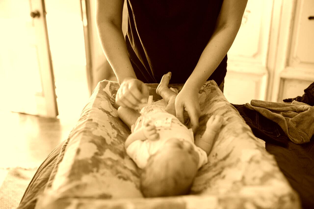 Foto envejecida de una madre cambiando el pañal a su bebé. | Foto: Pexels