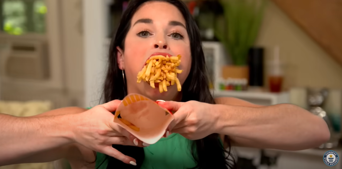 Samantha Ramsdell stuffing her mouth with a large-sized serving of French fries in a video dated July 28, 2021 | Source: youtube.com/guinnessworldrecords