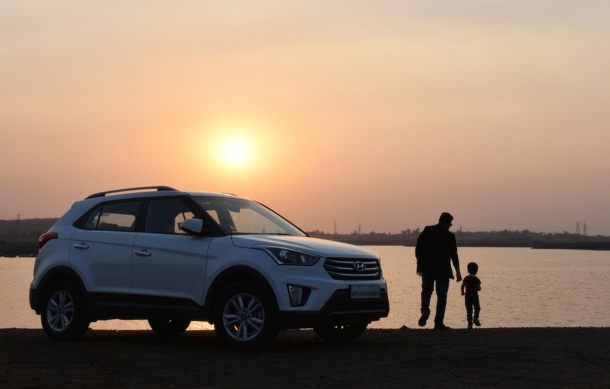 Man and child near a car with a sun setting in the background | Photo: Pexels