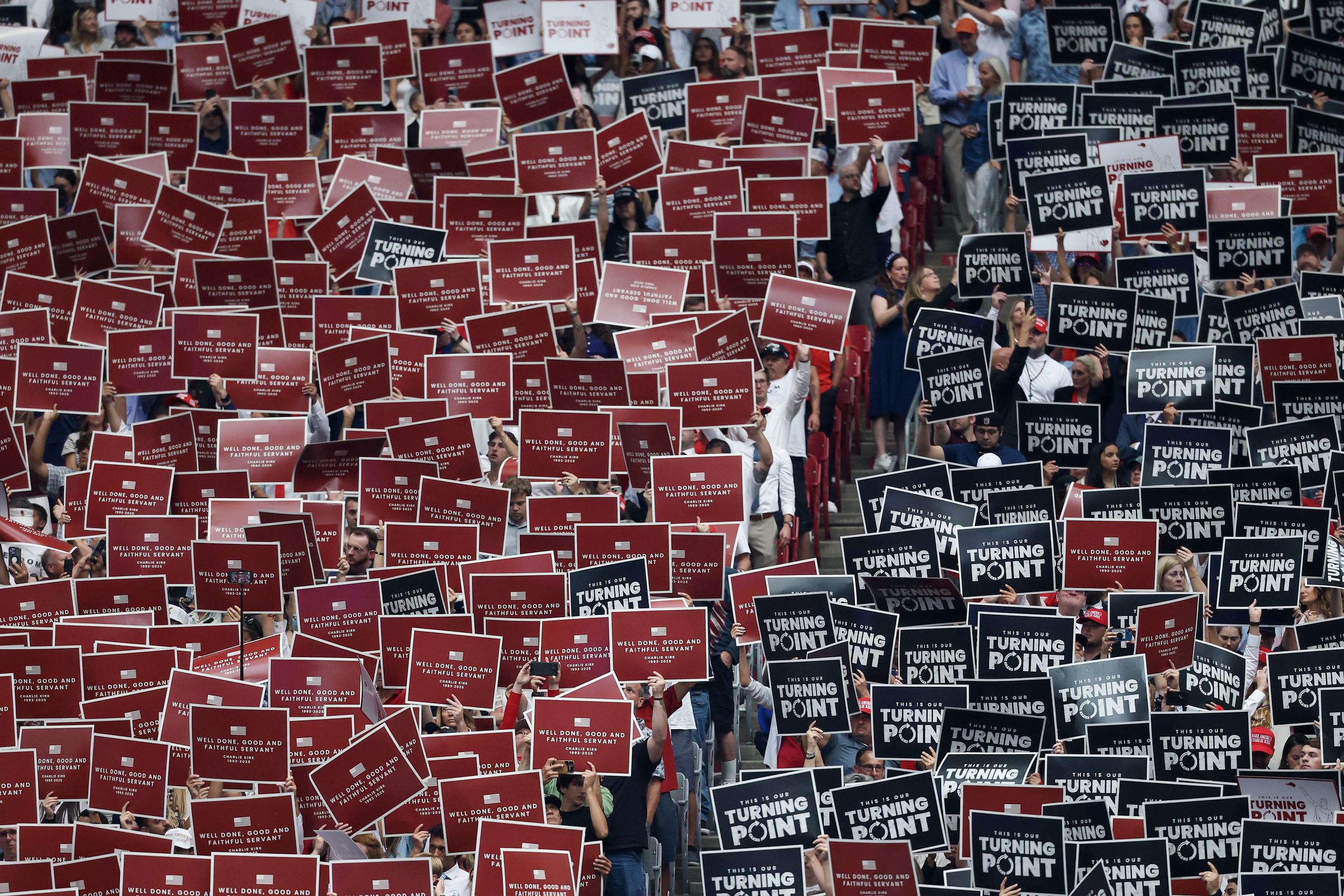Attendees hold up signs at the memorial service for Charlie Kirk at State Farm Stadium on September 21, 2025 in Glendale, Arizona | Source: Getty Images