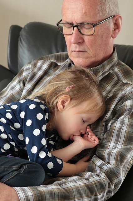 Young girl sleeps in elderly man's arms | Photo: Pixabay