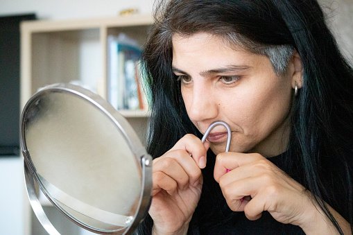 Femme arrachant sa moustache avec des pinces à épiler. | Photo : Getty Images